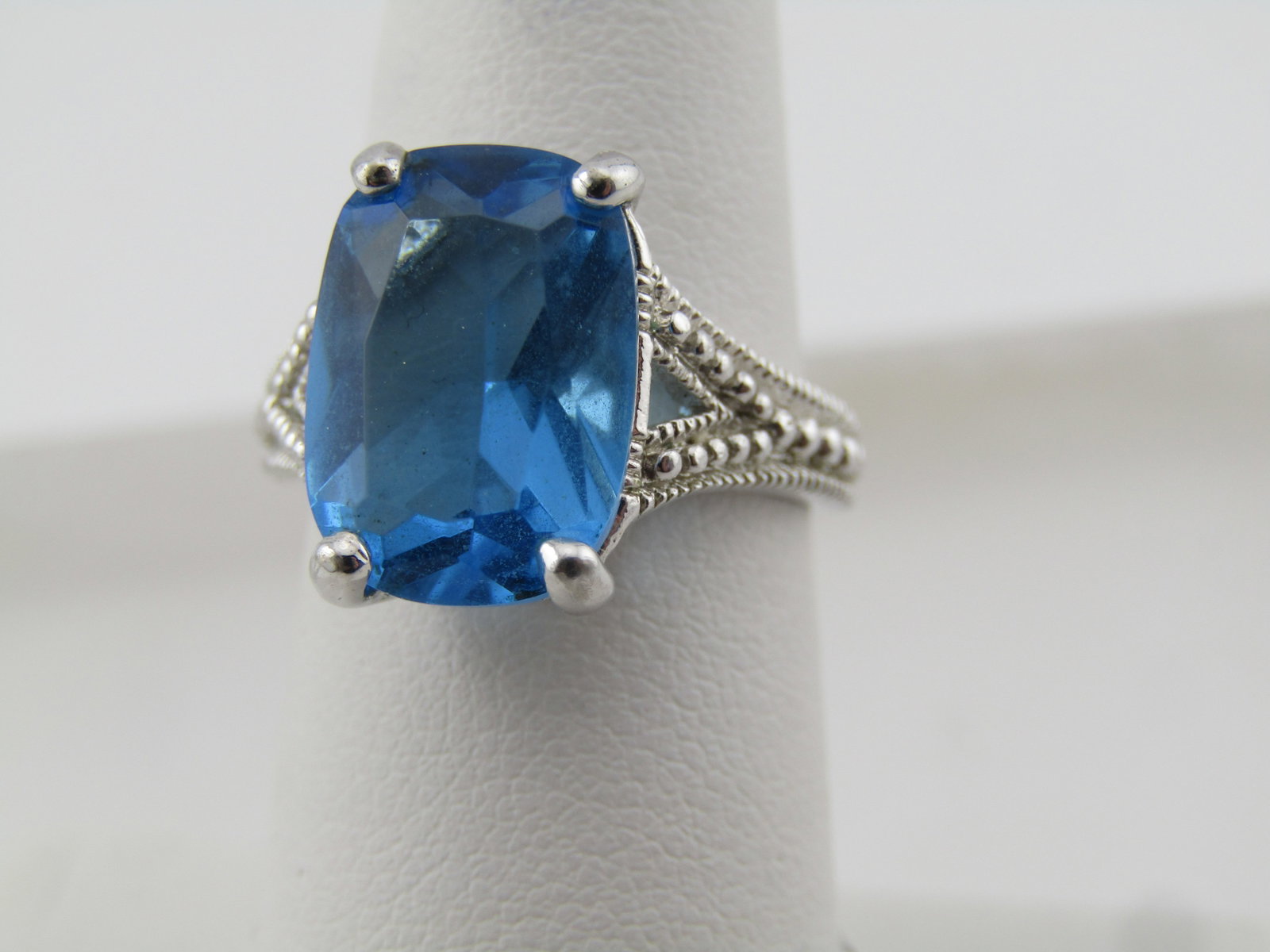 Silver Tone Blue Stone Ring, Sz. 6. 1990's: Title: Silver Tone Blue Stone Ring, Sz. 6. 1990's Description: Silver Tone Blue Stone Ring, Sz. 6. 1990's. This has a cushion cut rectangular blue stone that is prong-set and appx. 14mm by 9.5mm. It h