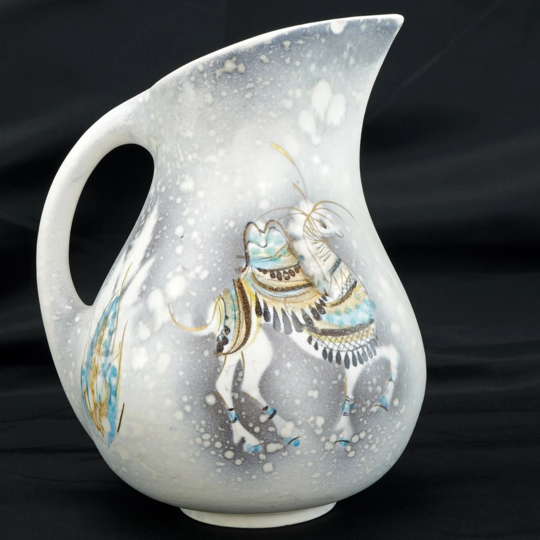 1950s Sascha Brastoff Pitcher Hand Painted: Title:1950s Sascha Brastoff Pitcher Hand Painted Size:6 in (15.2 cm) wide x 5 in (12.7 cm) diameter x 7 ¼ in (18.4 cm) tall. Description:A hand painted snowing scene with caparisoned camels in 