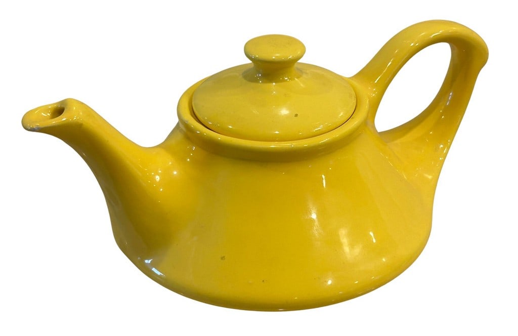 Bright Yellow Glazed Ceramic Teapot: A cheerful and brightly colored ceramic teapot, likely from the mid-20th century, with a vibrant yellow glaze. The teapot features a classic squat, rounded body, an elegant curved handle, and a gracef