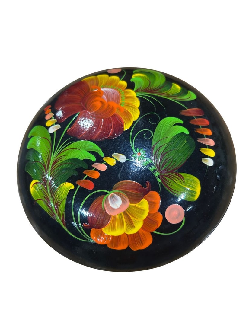 Hand-Painted Floral Lacquered Trinket Box: A charming hand-painted lacquered trinket box, possibly of Russian origin in the Khokhloma style. The black circular box features vibrant floral motifs in shades of red, orange, yellow, and green, cha