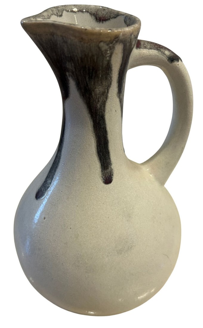 Handmade Studio Pottery Creamer Pitcher: A charming handmade studio pottery creamer pitcher, likely mid to late 20th century. The pitcher features a bulbous body with an applied handle and a flared spout. It is finished in a speckled off-whi