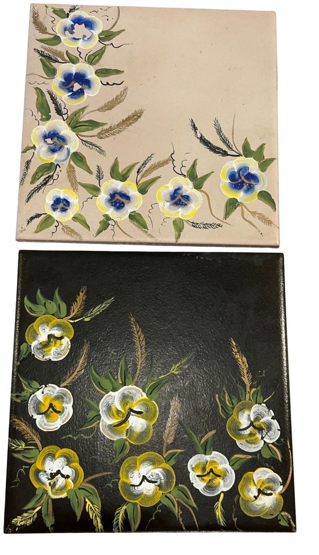 Hand-Painted Floral Ceramic Tiles, Set of 2: This lot features a set of two hand-painted ceramic tiles, each adorned with vibrant floral motifs. One tile presents a light beige background with blue, yellow, and white flowers accented by green fo