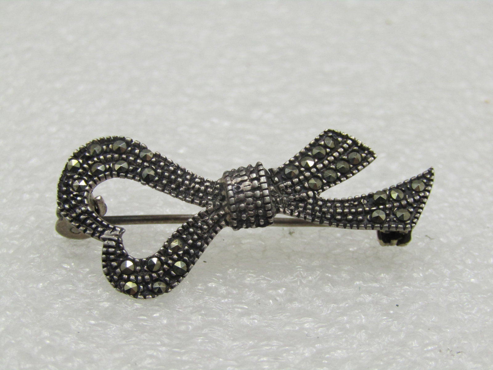 Vintage Sterling Marcasite Heart Bow Brooch: Title: Vintage Sterling Marcasite Heart Bow Brooch Description: Vintage Sterling Marcasite Heart Bow Brooch, 2.5" by 3/4". Not marked or signed. There is some damage on the back with a crack but is st