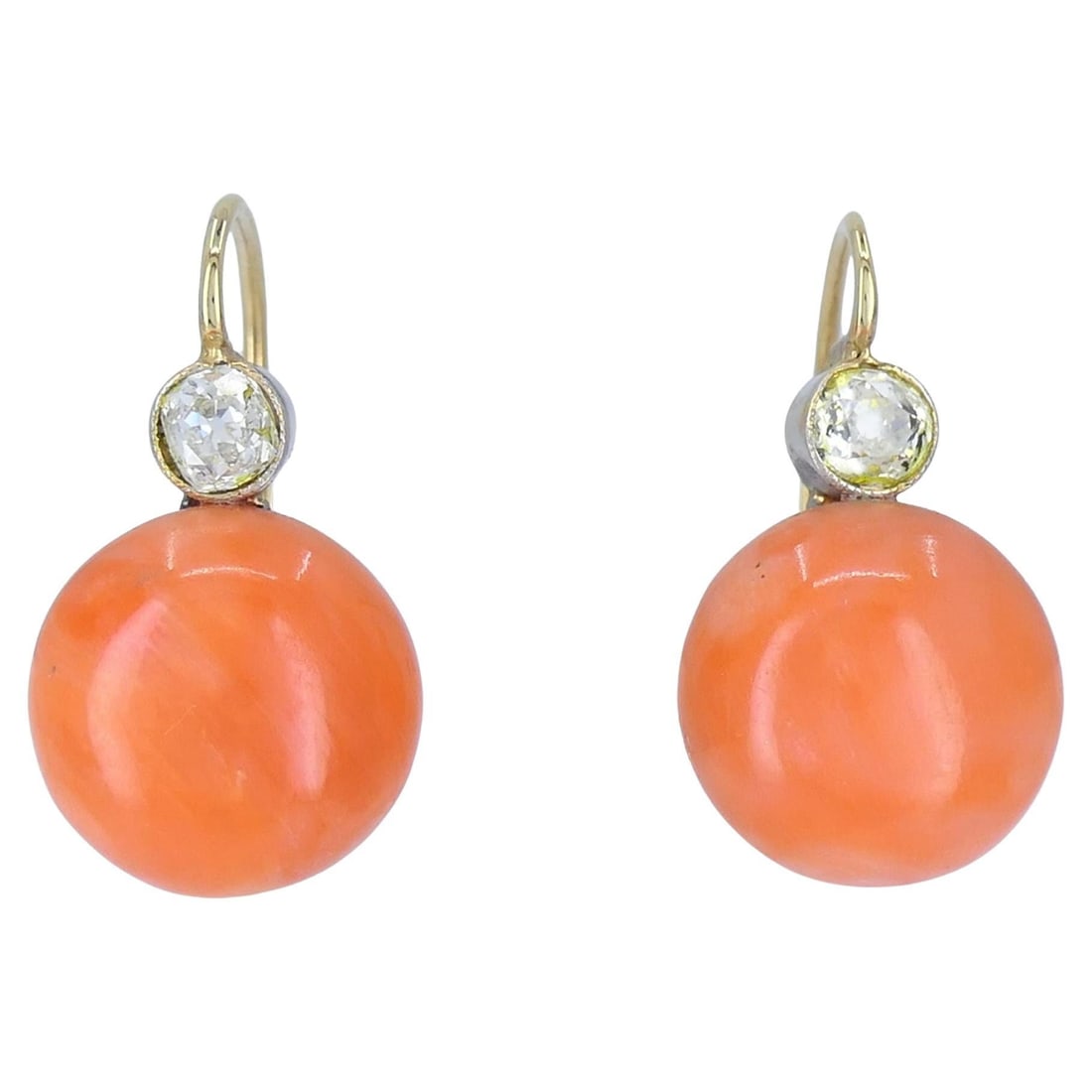 Vintage Mid-Century 14k Gold Coral Diamond Drop Earrings: These circa mid 20th century coral and diamond drop earrings are crafted in 14k white and yellow gold and feature luminous round coral cabochons suspended beneath sparkling diamonds. The diamonds are