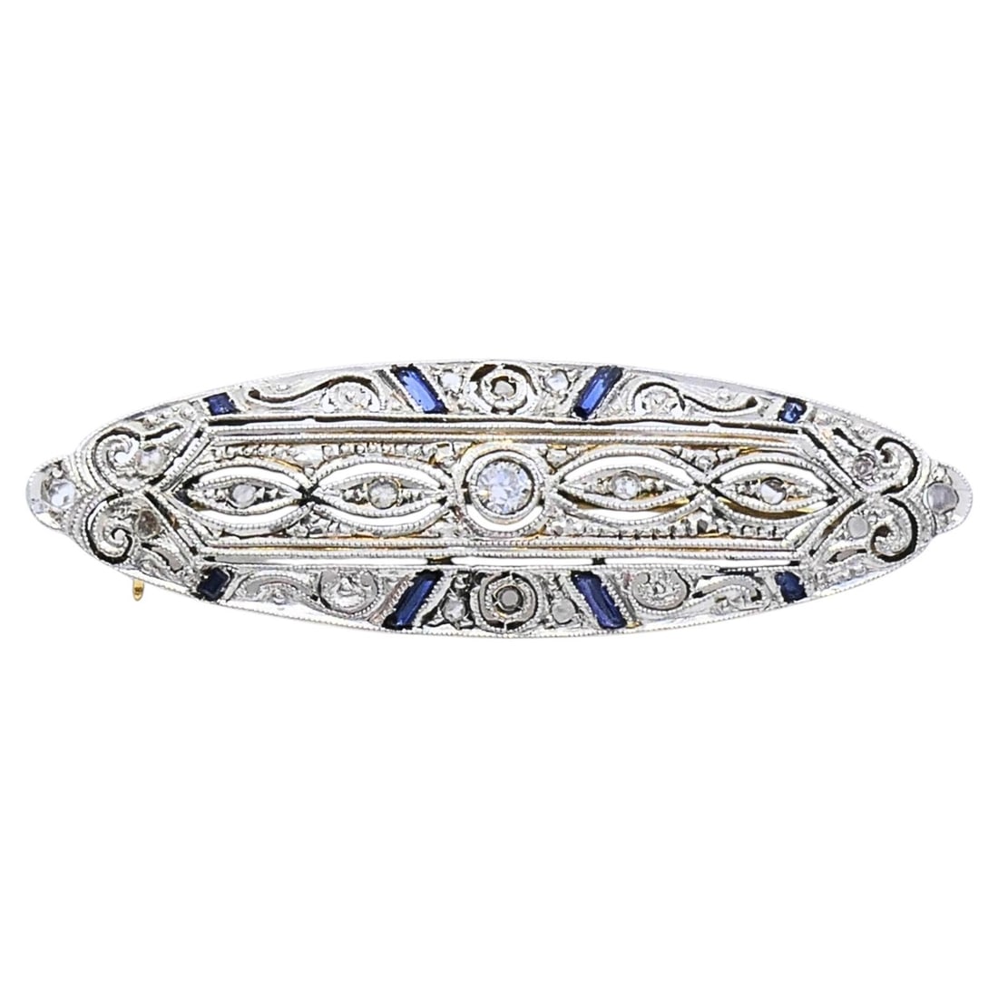 Art Deco 18k Gold Diamond Sapphire Navette Brooch: An Art Deco brooch in 18k gold, set with diamonds and blue sapphires in an elongated navette shape. The surface shows open milgrain filigree work with a central diamond flanked by smaller stones along