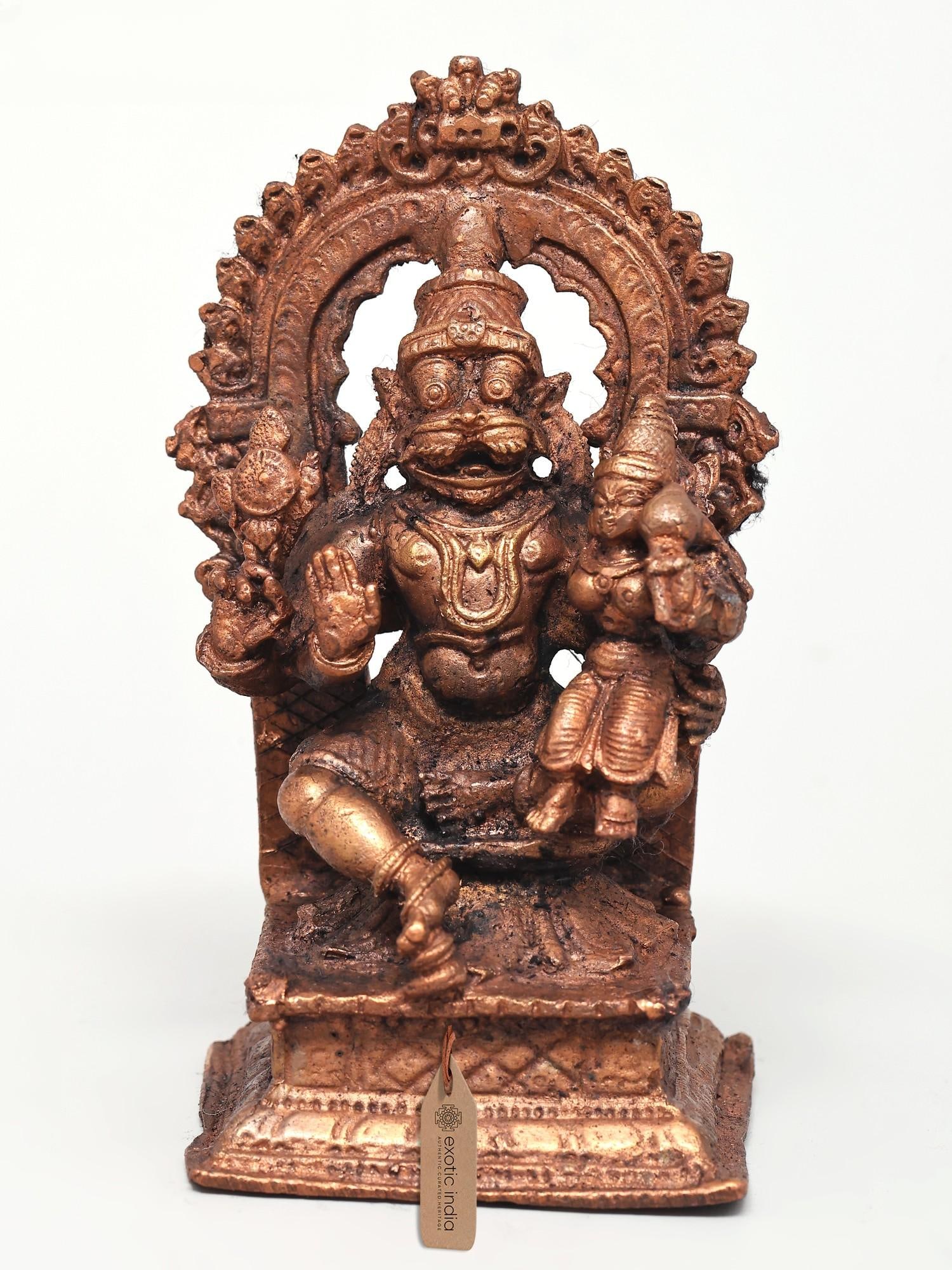4" Small Lord Narasimha Seated on Kirtimukha Throne with Devi Lakshmi | Copper Statue: The Divine Embrace: Lord Narasimha and Devi Lakshmi This exquisite copper statue captures a profound moment of divine grace and power. Lord Narasimha, the man-lion avatar of Vishnu, is depicted