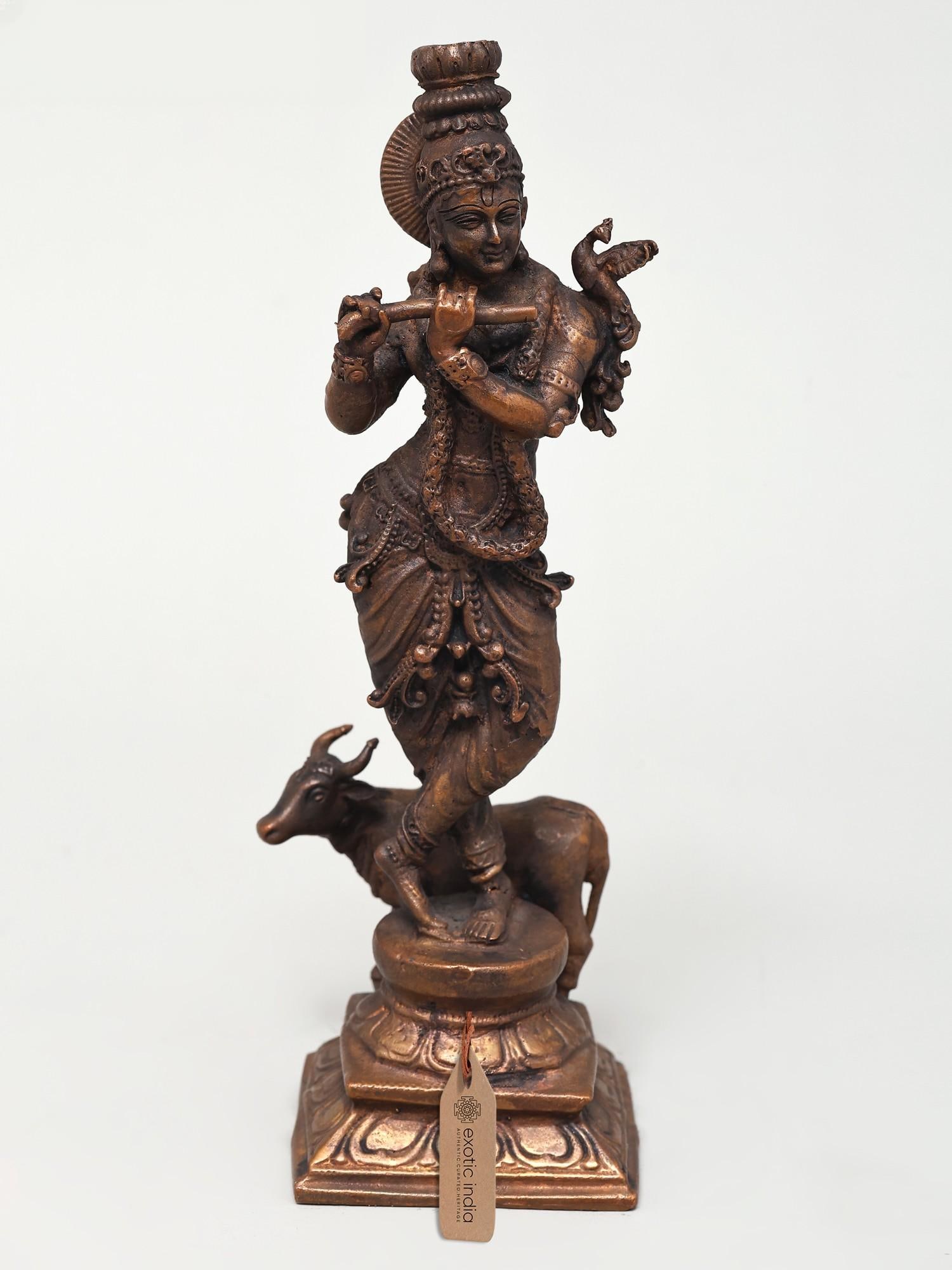 7" Standing Venugopal Krishna with Cow | Copper Statue: The Enchanting Melodies of Divine Love This exquisite copper statue captures the divine presence of Lord Krishna, the beloved deity of Vrindavan, in his iconic form as Venugopal. The term "Venugopal" 