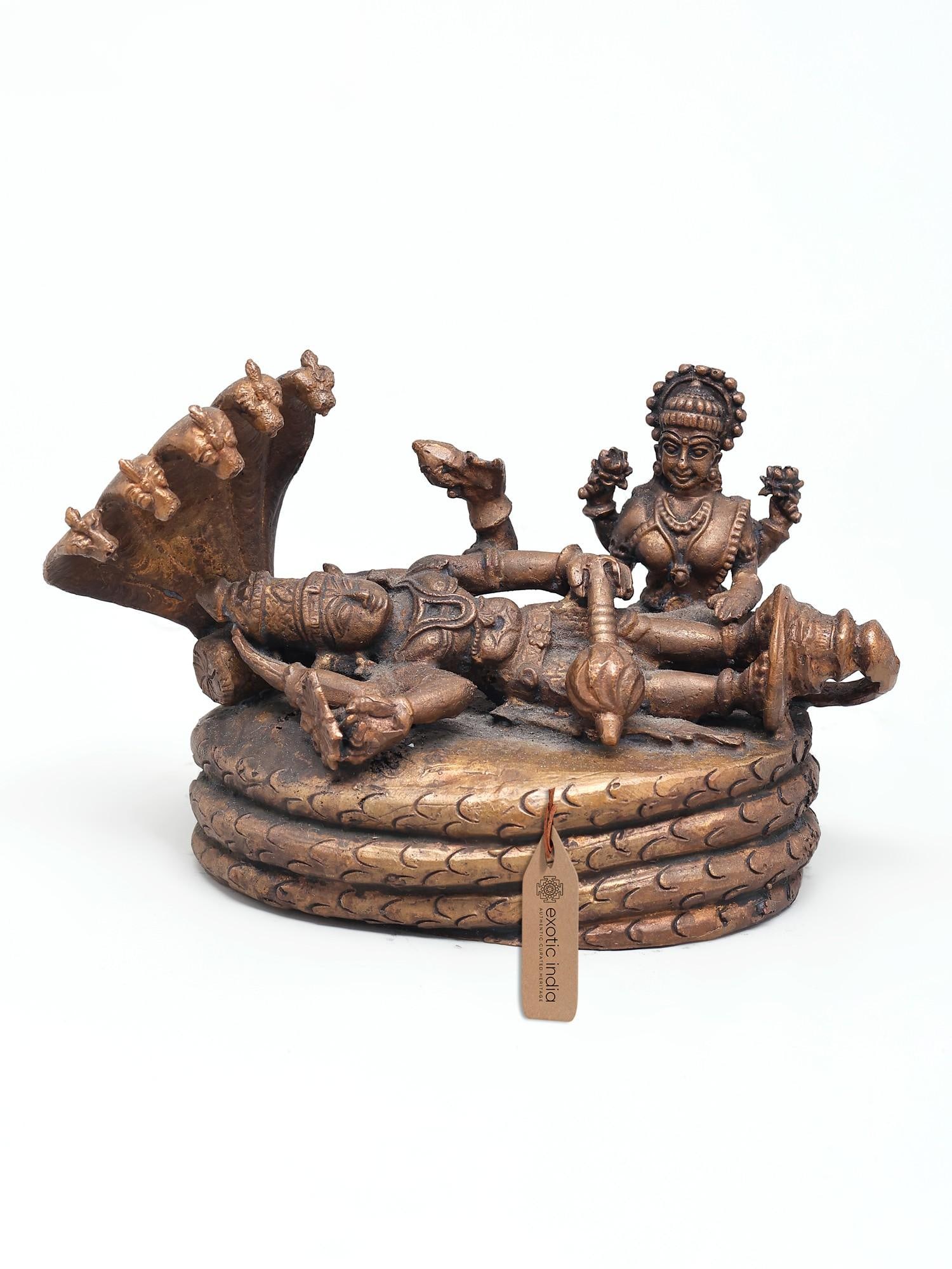5" Small Shesha-Shayi Lord Vishnu with Devi Lakshmi | Copper Statue: The Divine Slumber and Cosmic Creation This exquisite copper statue captures the profound and iconic imagery of Lord Vishnu in his celestial repose upon the coils of the serpent Shesha, also known as