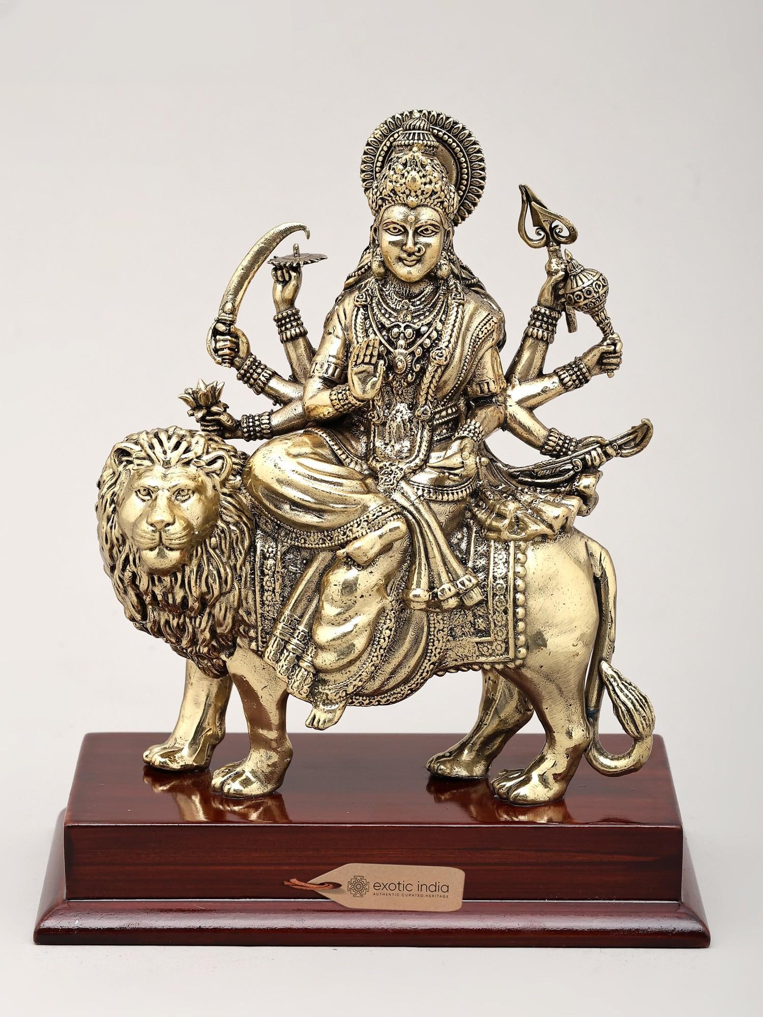 Superfine Ashtabhuja Goddess Durga Seated on Lion with Wood Base | Brass Sculpture | Made in India: The Divine Mother: A Symbol of Power and Grace This exquisite brass sculpture captures the awe-inspiring presence of Goddess Durga, the primordial mother and the invincible warrior, in her form as