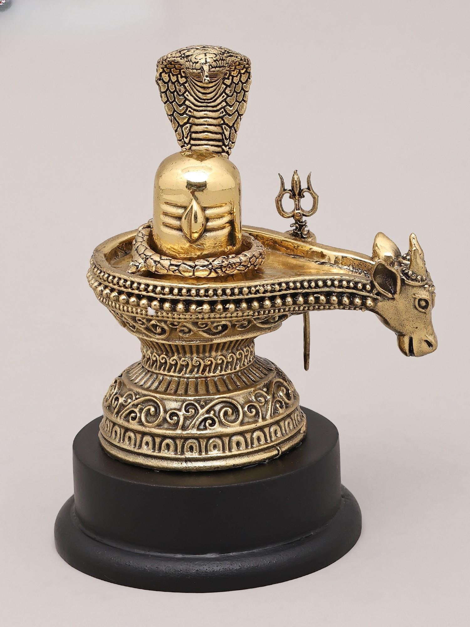 5" Small Superfine Brass Statue of Shiva Lingam with Nandi, Trident and Vasuki Naag with Wood Base |: Embodiment of Divine Power and Serenity This exquisite brass statue captures the multifaceted essence of Lord Shiva, one of the most revered deities in Hinduism. The central element is the Shiva Linga