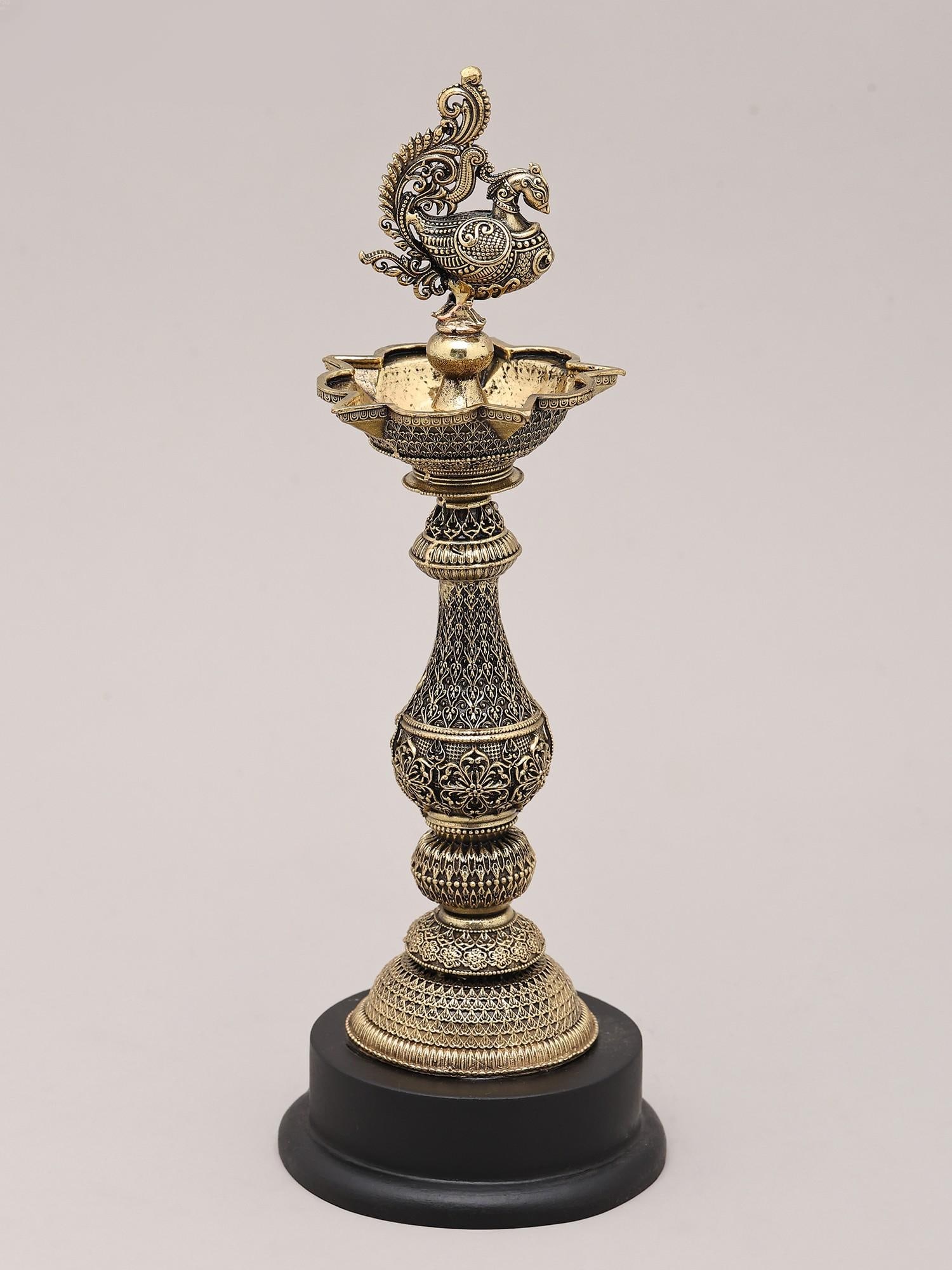 9" Peacock Brass Oil Lamp with Wood Base for Home and Temple | Made in India: The Peacock's Radiant Glow: An Emblem of Auspiciousness This exquisite brass oil lamp, adorned with a majestic peacock, is a testament to the rich artistic heritage of India. More than just a source