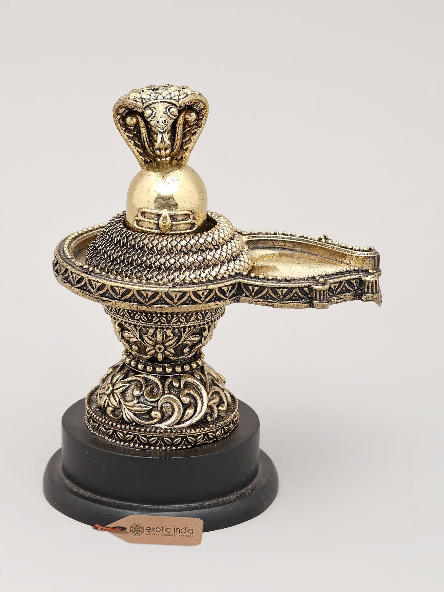 5" Small Superfine Shivling and Protective Vasuki with Wood Base | Brass Statue | Made in India: Divine Presence: The Auspicious Shivling with Vasuki Embrace the divine energy of Lord Shiva with this exquisitely crafted brass statue, depicting the sacred Shivling crowned by the protective embrace