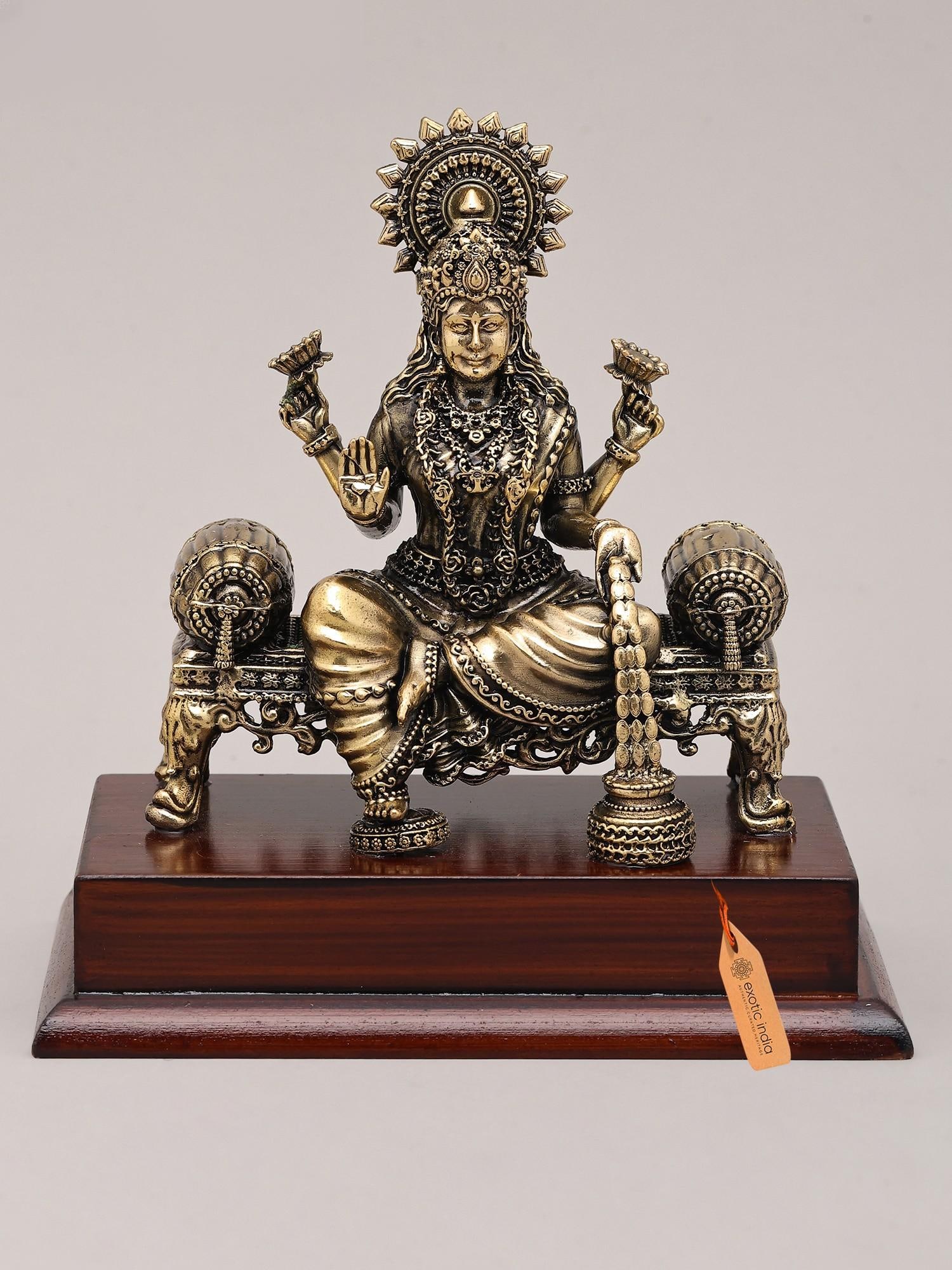 5" Superfine Goddess Dhanalakshmi Seated on Asana with Wood Base | Brass Statue: Embodiment of Divine Prosperity This exquisite brass statue captures the divine essence of Goddess Dhanalakshmi, the benevolent bestower of wealth, fortune, and abundance. Seated gracefully upon an