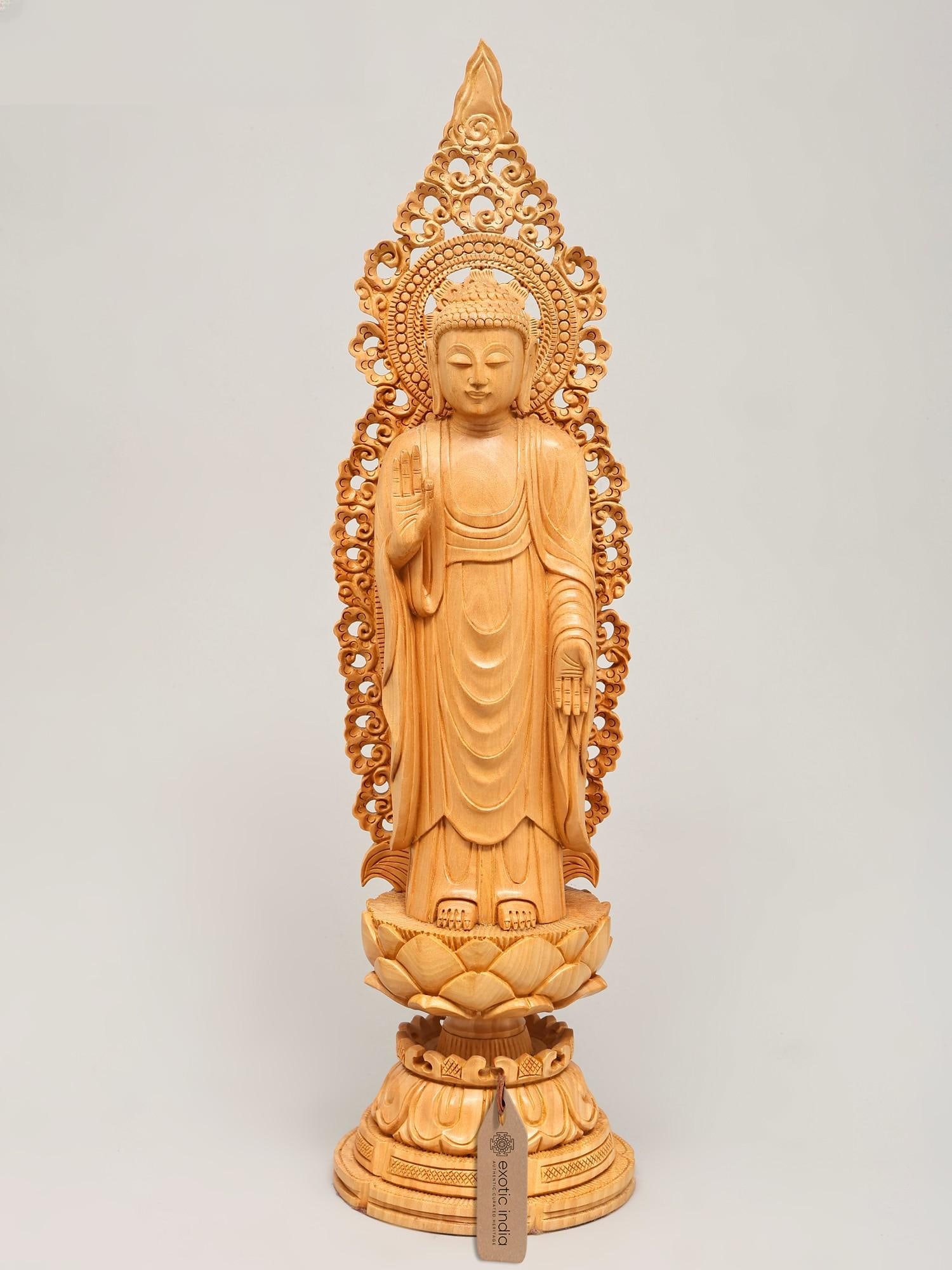 18" Standing Lord Buddha in Vitark Mudra on Lotus Pedestal | Wood Carved Statue: Embodying Enlightenment: A Lord Buddha Statue in Vitark Mudra Invite serenity and wisdom into your home or meditation space with this exquisite wood-carved statue of Lord Buddha. Standing tall at eigh