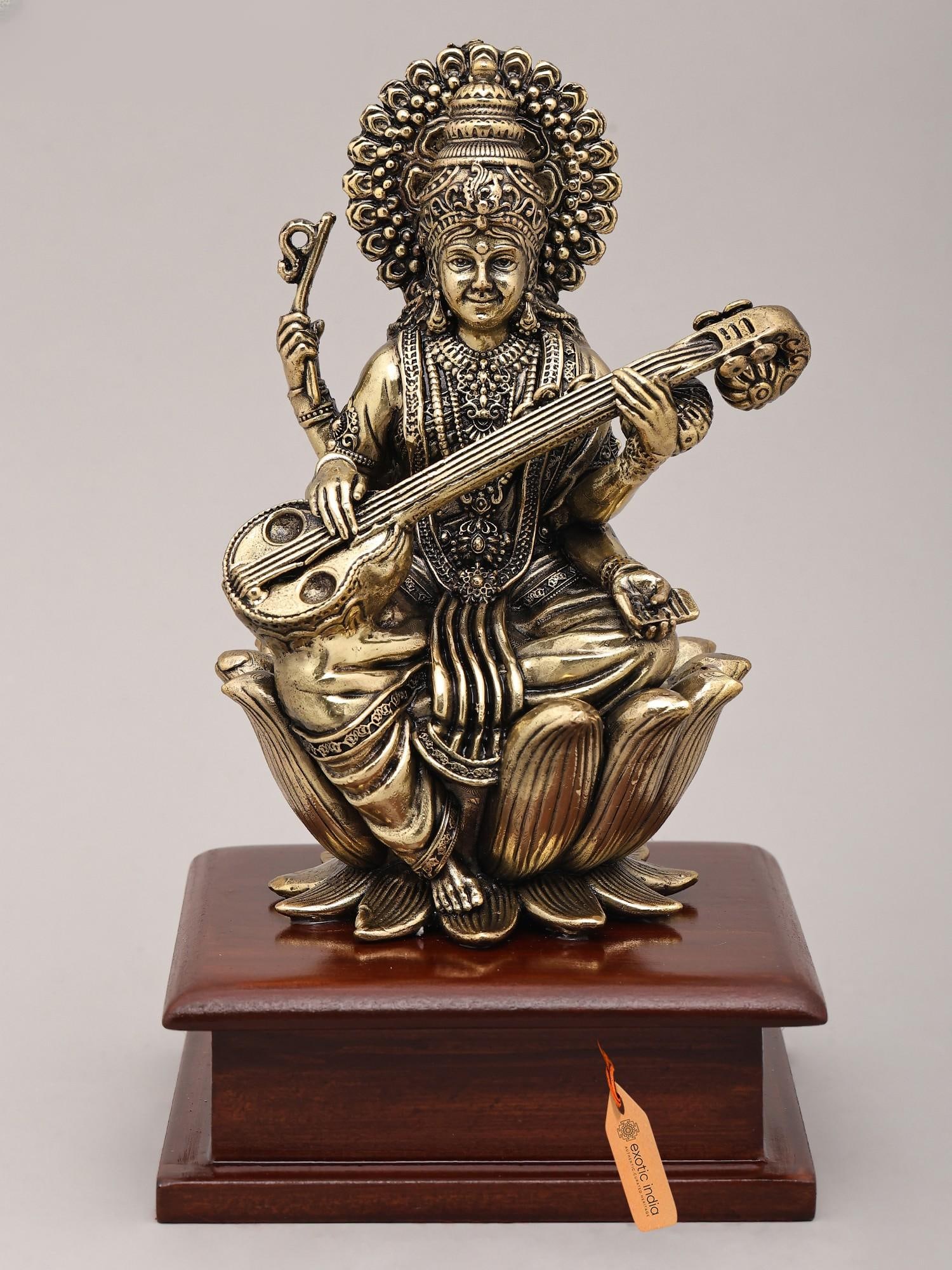Superfine Seated Four Armed Goddess Saraswati with Wood Base | Brass Idol: The Embodiment of Wisdom and Artistry This exquisite brass idol captures the divine grace and profound symbolism of Goddess Saraswati, the Hindu deity of knowledge, music, art, speech, and wisdom.