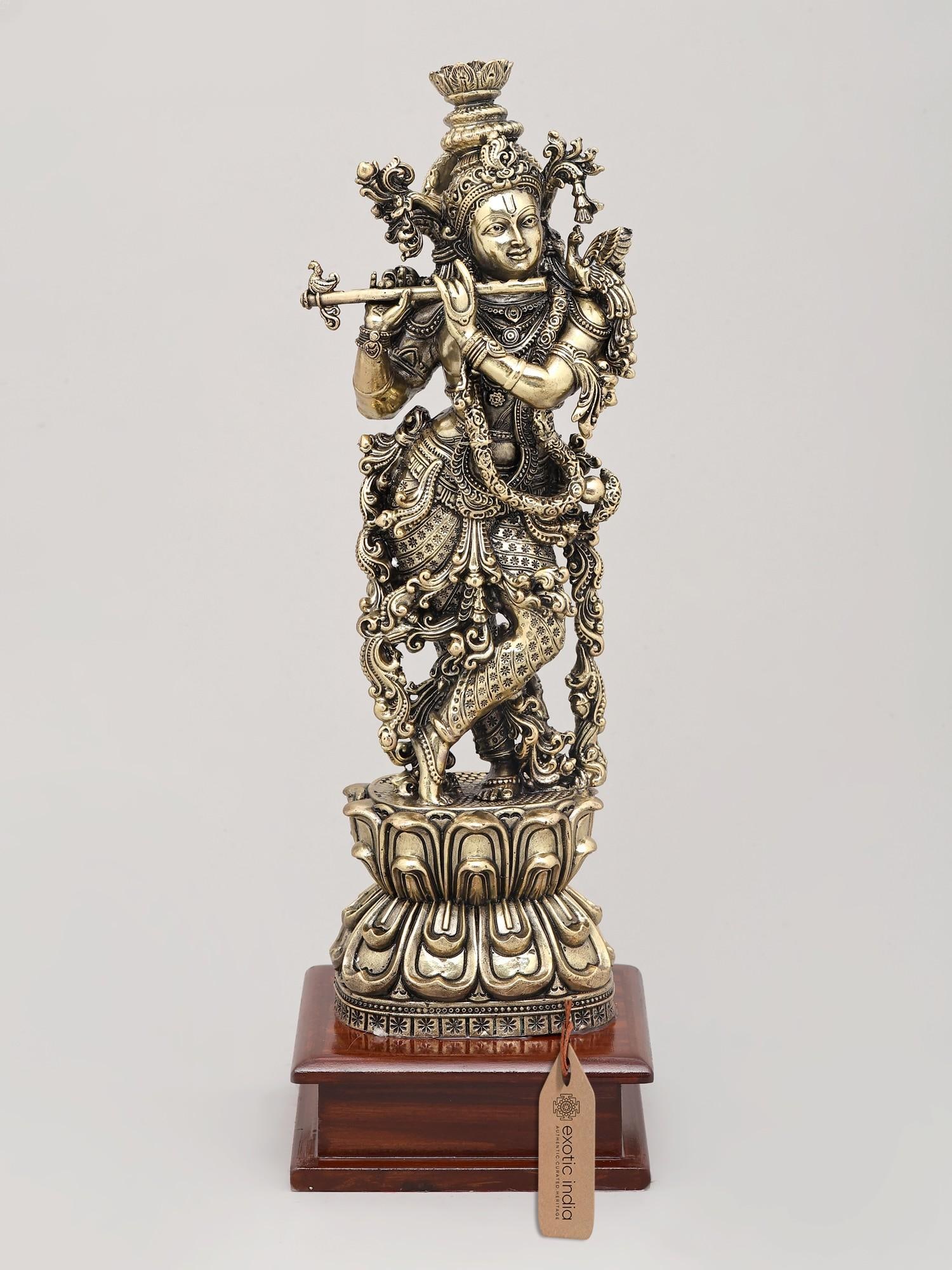 13" Superfine Lord Krishna with Flute - The Divine Musician with Wood Base | Brass Idol: The Divine Maestro of Vrindavan Behold a magnificent depiction of Lord Krishna, the divine cowherd, the enchanting flutist, and the revered deity of love, joy, and spiritual bliss. This exquisitely cr