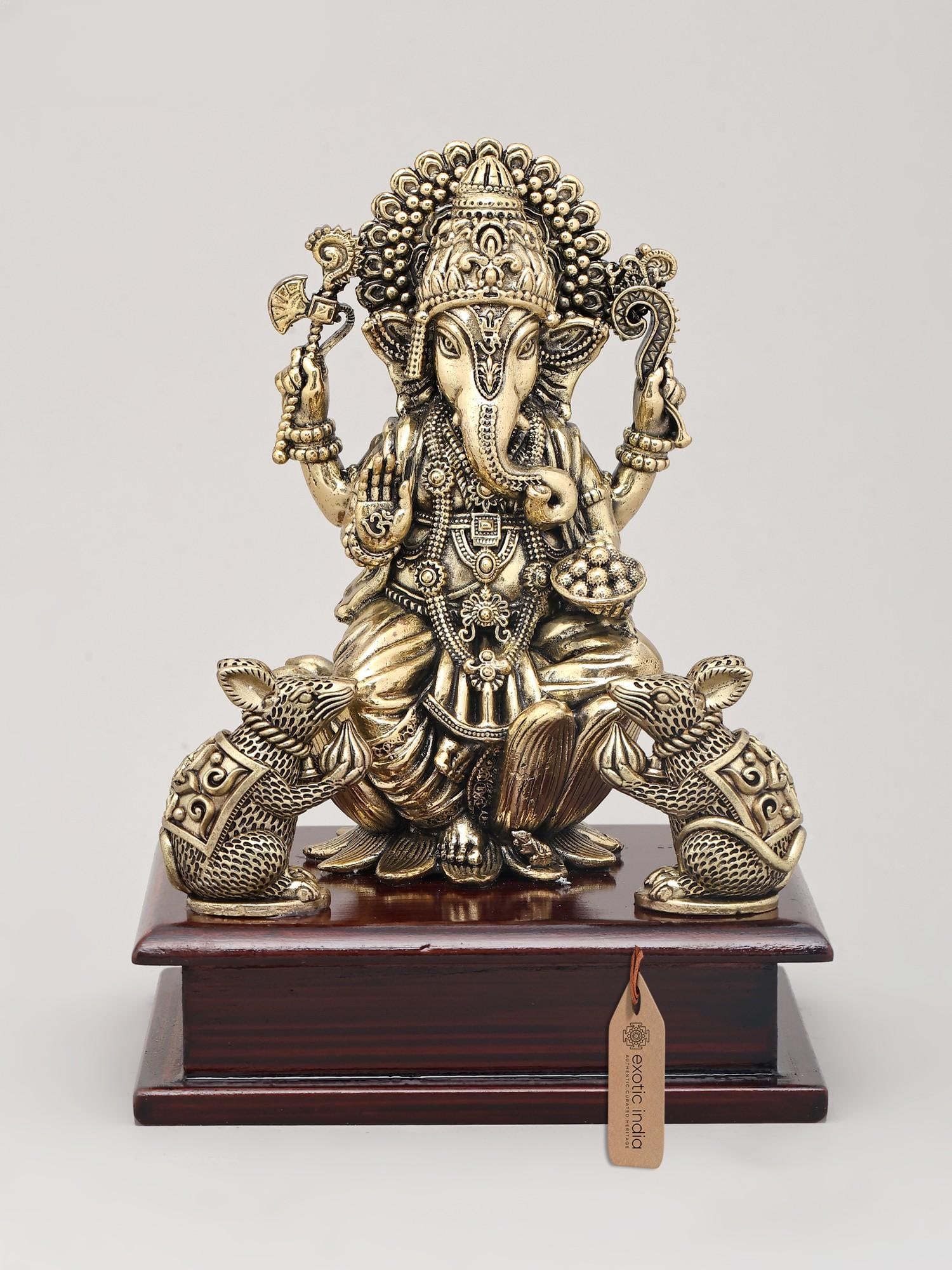 7" Superfine Four Armed Majestic Lord Ganesha with Dual Mushak on Wood Base | Brass Idol: The Auspicious Presence of Lord Ganesha This exquisite brass idol captures the divine essence of Lord Ganesha, the remover of obstacles and the bestower of wisdom and prosperity. Seated majestically, 