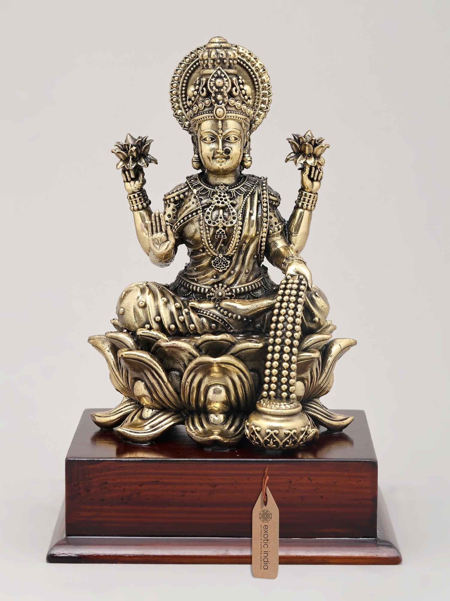 7" Superfine Goddess Lakshmi - Deity of Wealth Seated on Lotus with Wood Base | Brass Idol: Embodying Prosperity and Auspiciousness Invite the benevolent presence of Goddess Lakshmi, the divine embodiment of wealth, prosperity, and good fortune, into your home with this exquisite superfine