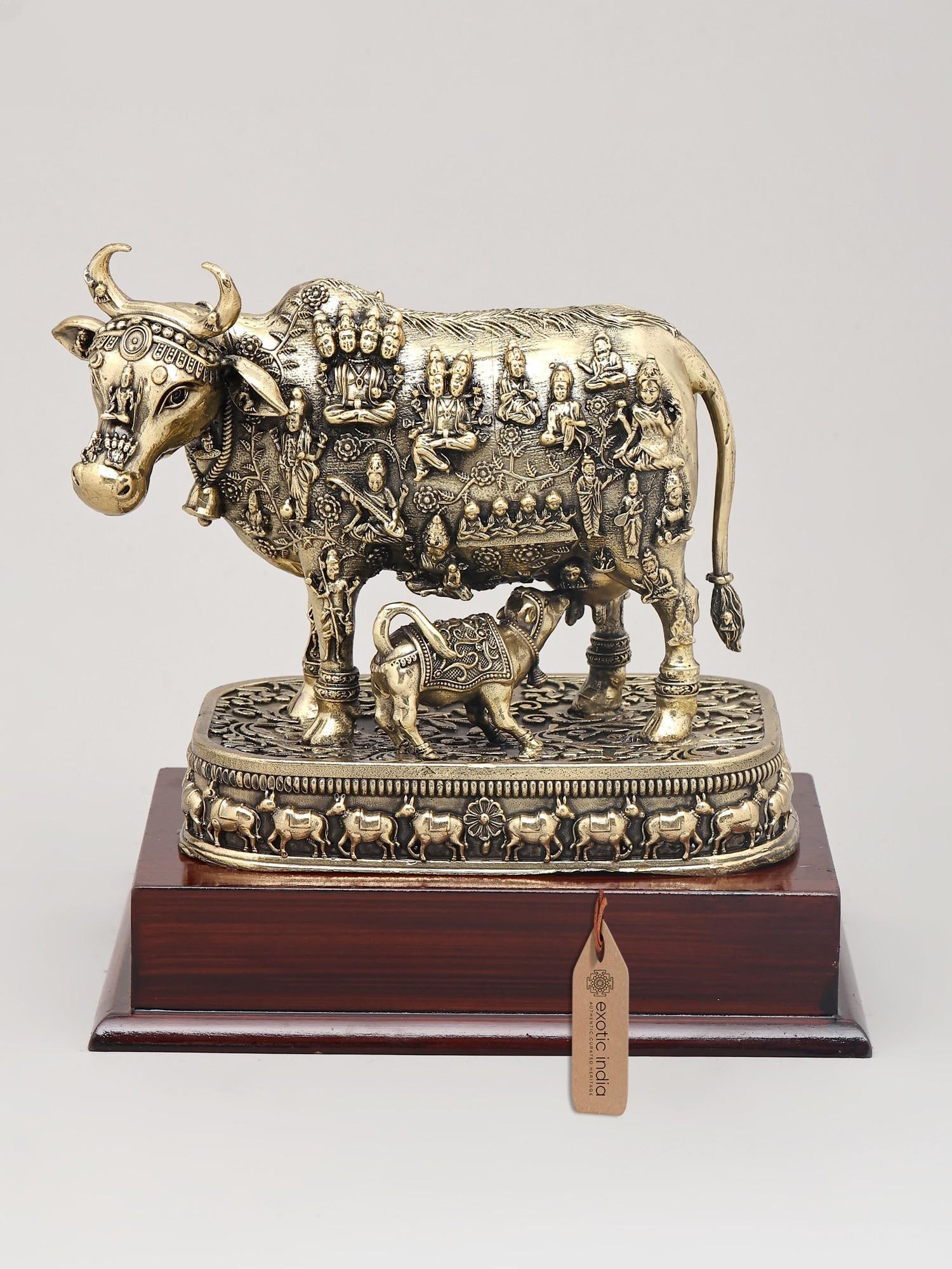 Small Superfine Kamdhenu Cow and Calf with Engraved Many God and Goddess on Wood Base | Brass: A Symbol of Abundance and Divinity This exquisite brass figurine captures the essence of Kamdhenu, the divine wish-fulfilling cow of Hindu mythology, and her calf. Kamdhenu is revered as the mother of