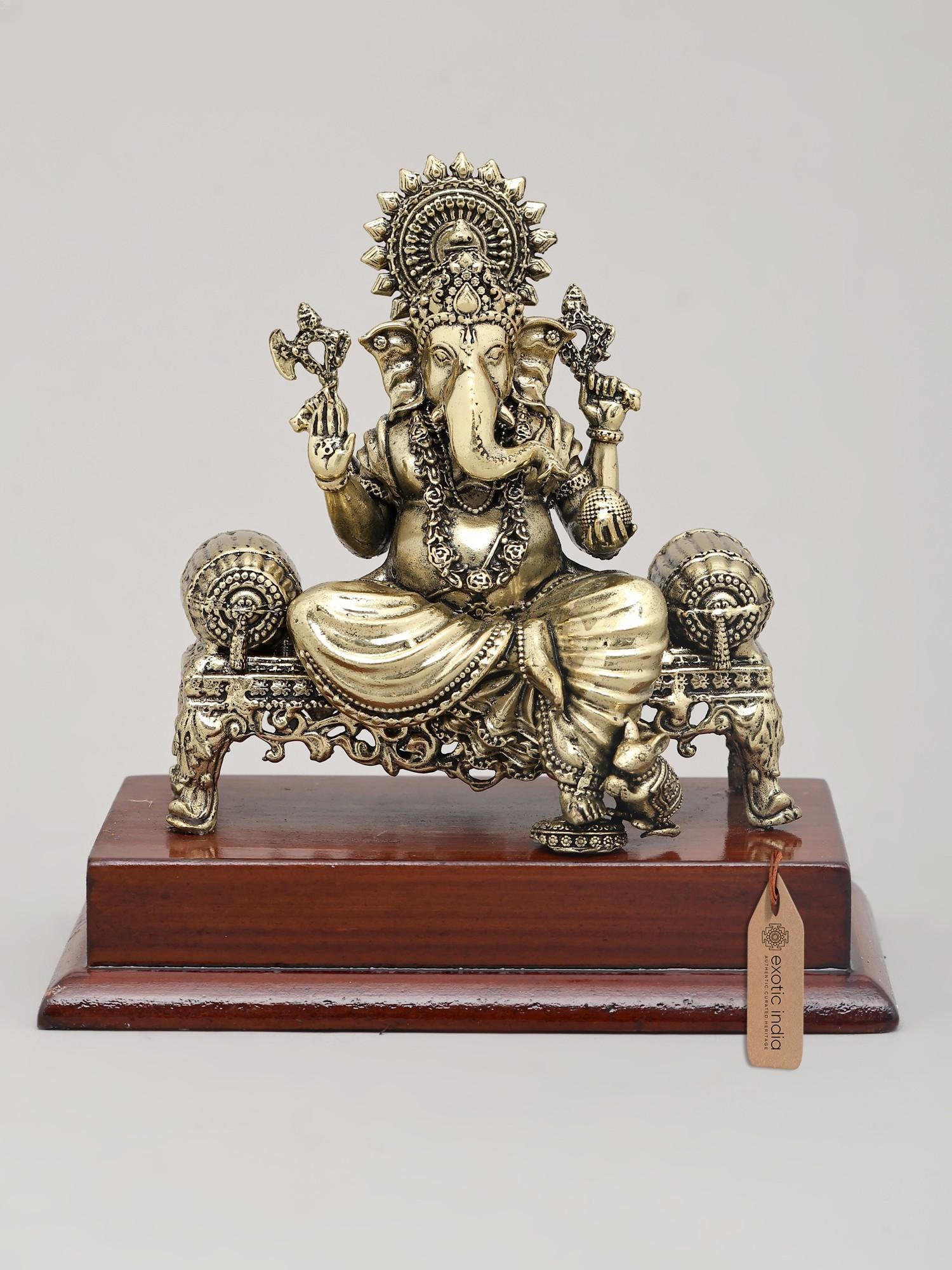 5" Small Superfine Lord Ganesha Seated on Ornate Throne with Wood Base | Brass Idol: Embrace Divine Wisdom and Prosperity Invite the auspicious presence of Lord Ganesha into your home with this exquisite superfine brass idol. Seated majestically on an ornate throne, this divine repres