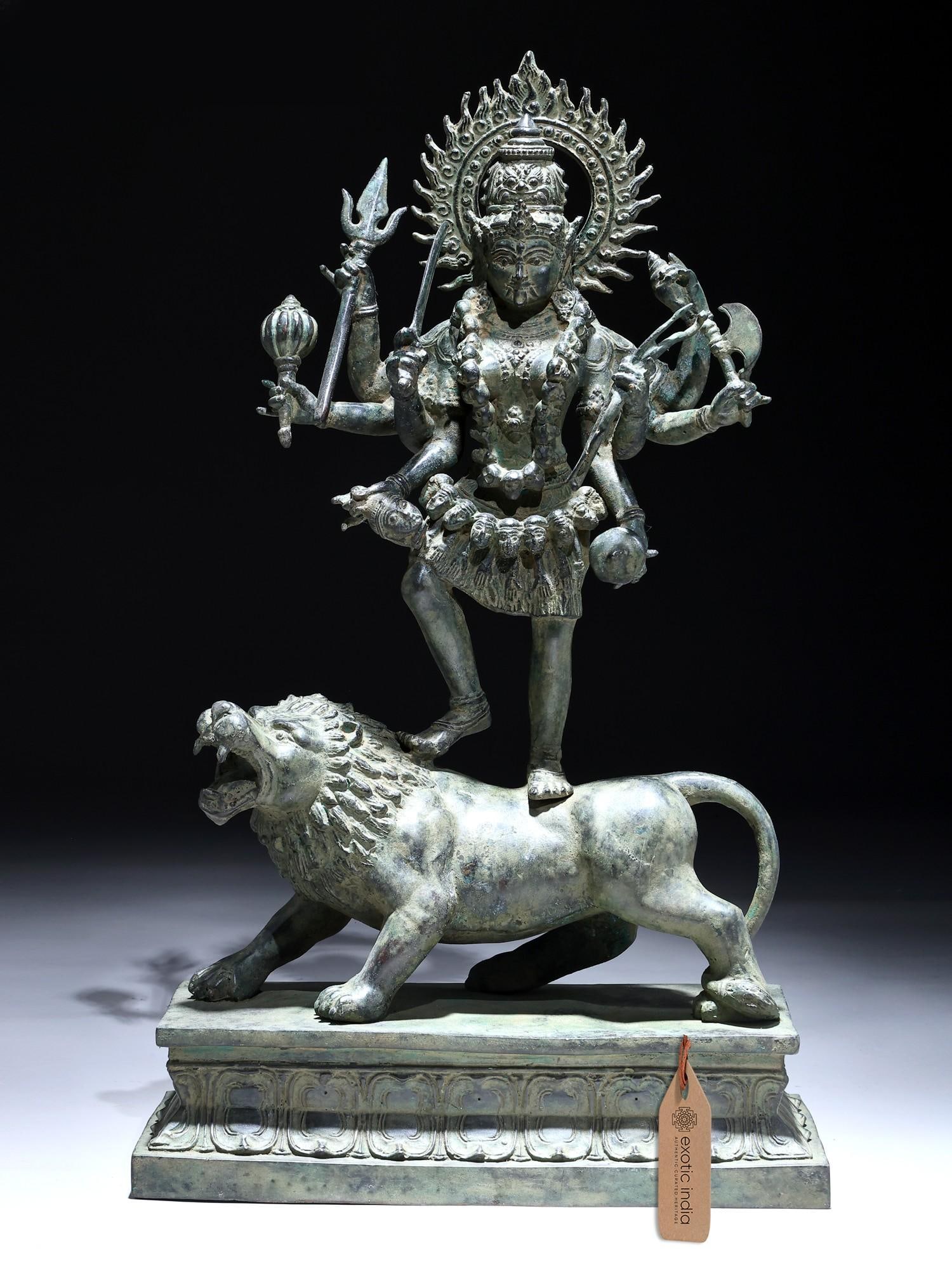 21" Eight Armed Goddess Mahakali Standing on Roaring Lion | Balinese Brass Statue | Made in India: The Fierce Embodiment of Divine Power This magnificent brass statue captures the awe-inspiring form of Mahakali, the fierce aspect of the Divine Mother in Hinduism. Her eight arms, outstretched in a d