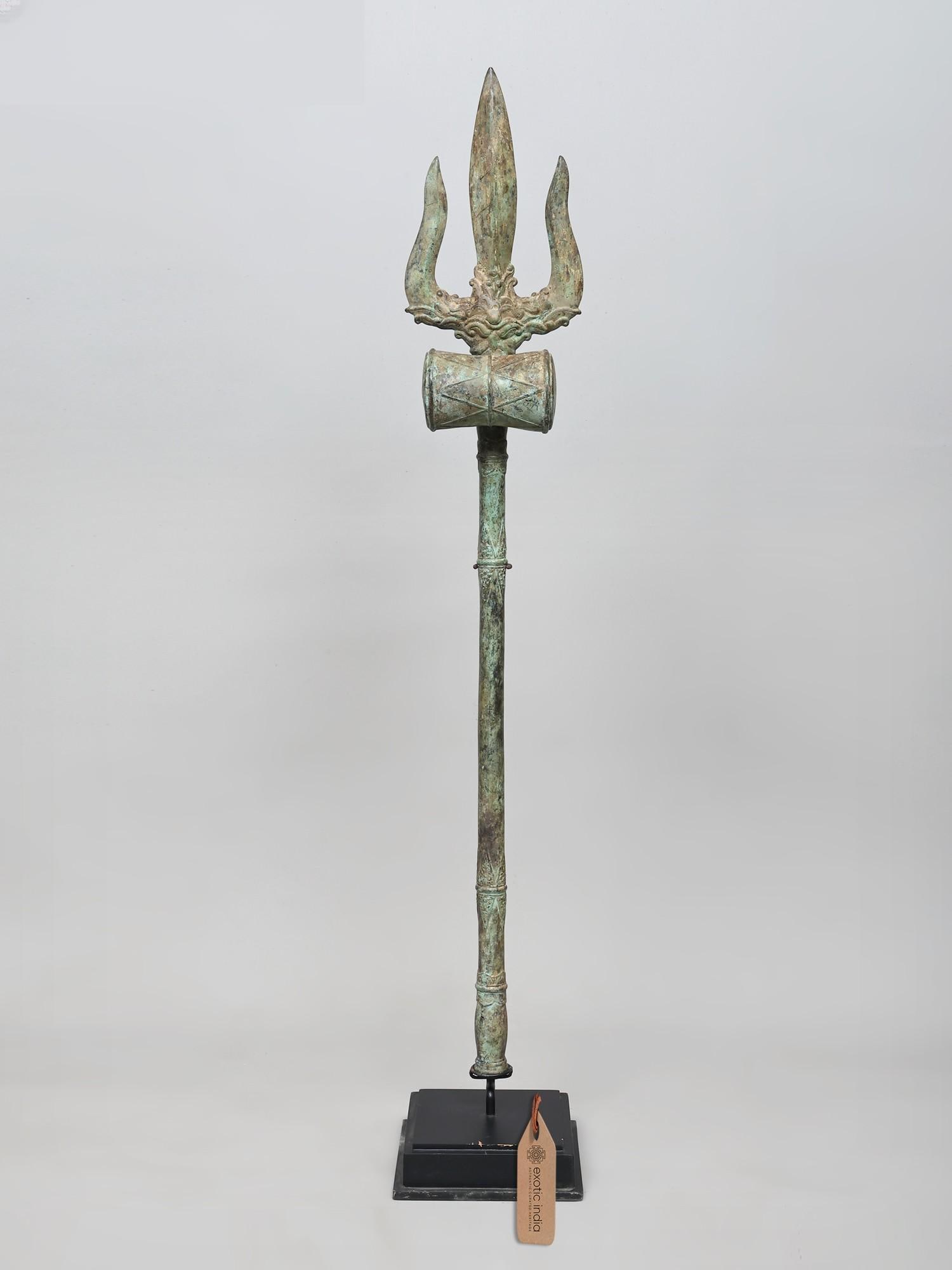 46" Large Brass Trident of Lord Shiva on Wood Base: A Symbol of Divine Power and Cosmic Balance This magnificent brass trident, standing at an impressive 46 inches, is more than just a decorative piece; it is a powerful representation of Lord Shiva,
