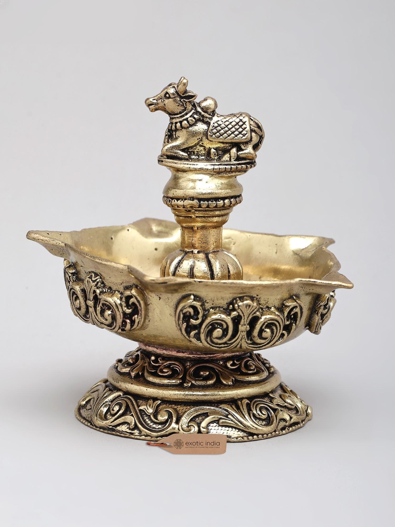 3" Small Superfine Five Wicks Lamp with Nandi on Top: An Emblem of Divine Presence and Auspicious Illumination This exquisite brass lamp is more than just a source of light; it is a sacred artifact that embodies profound spiritual significance and