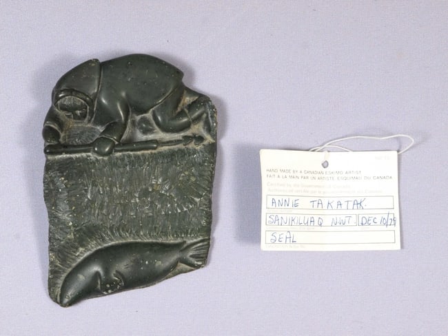 Inuit Canada Native Canadian Soapstone Carving Man Seal SIGNED Annie Takatak: This is a vintage Native American Eskimo Inuit Figurine.It was made by Annie Takatak, from Belcher Islands, Canada.The figurine is made from soapstone and is very unusual. It is a plaque with flat bac