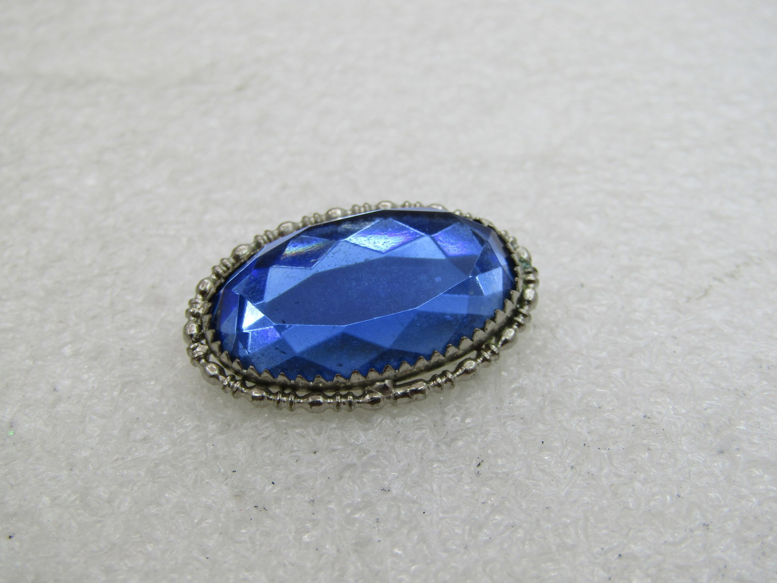 Vintage 10kt Plated Blue Rhinestone Brooch, C-Clasp, 1": Title: Vintage 10kt Plated Blue Rhinestone Brooch, C-Clasp, 1" Description: Vintage Blue Rhinestone Brooch, C-Clasp, 10kt white gold plated. 1" wide and 3/4" tall. Blue glass facted oval stone with a 