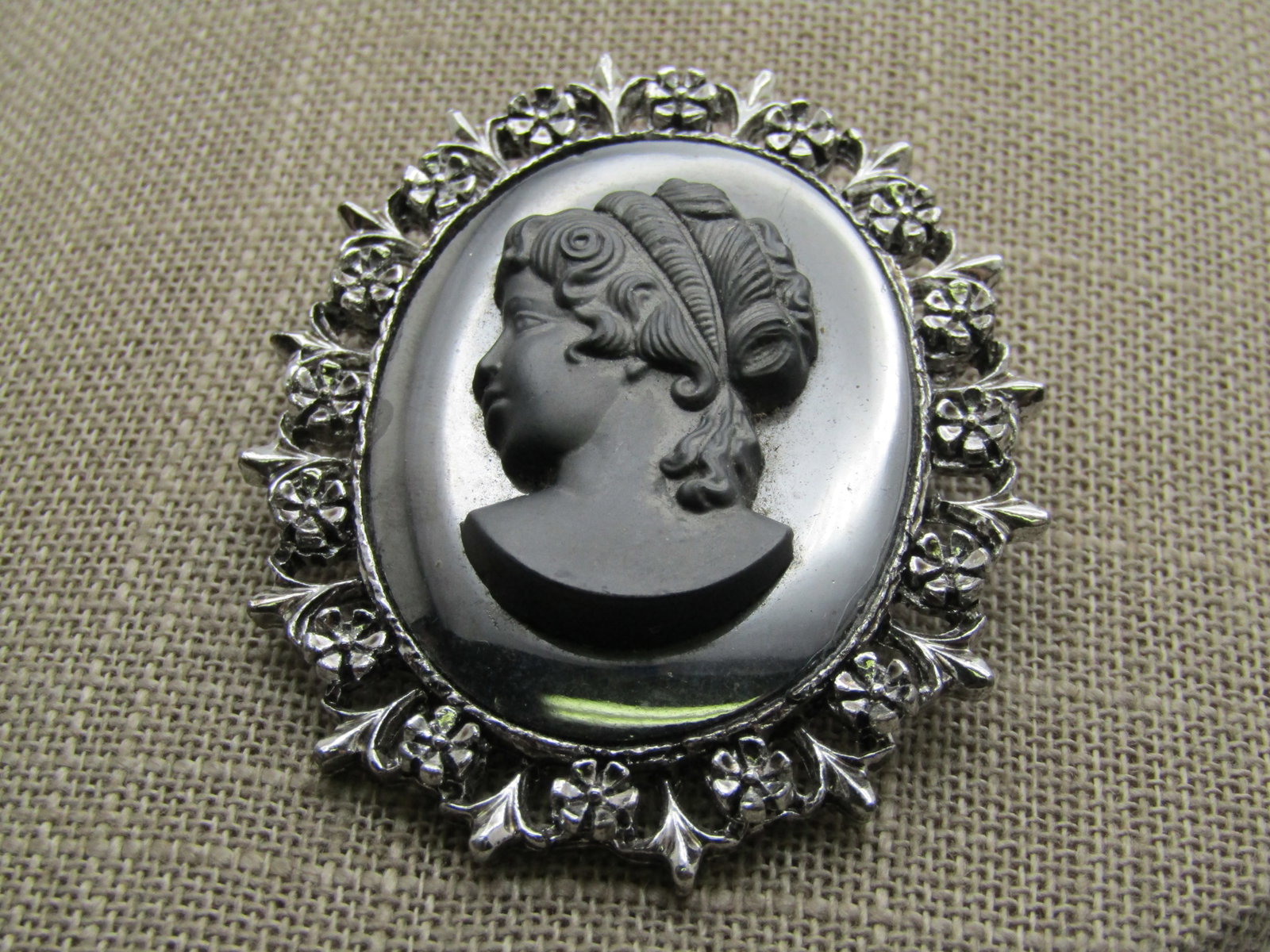 Vintage Hematite Cameo Brooch, 1960's-1970's, 2": Title: Vintage Hematite Cameo Brooch, 1960's-1970's, 2" Description: Vintage Hematite Cameo Brooch, 1960's-1970's, 2". Silver tone with a floral and fleur-de-lis frame and a hematite refelctive style