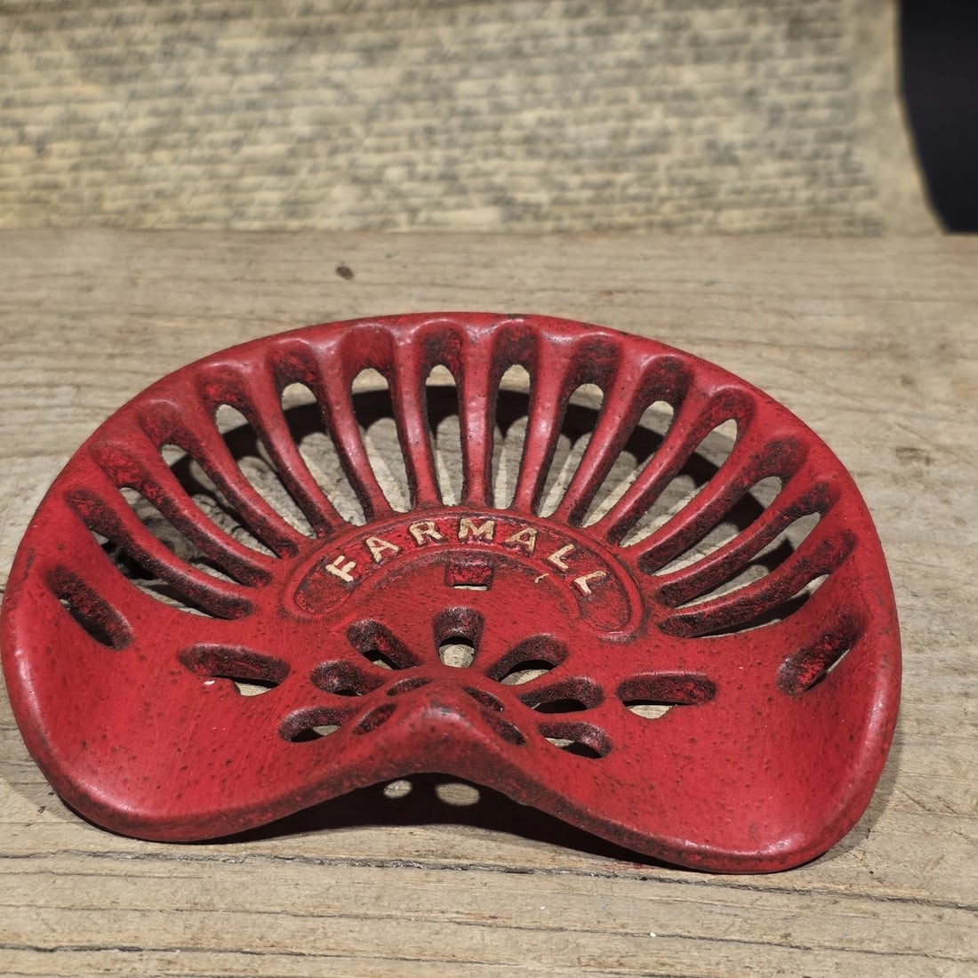 5" Mini Farmall Cast Iron Tractor Seat - Red IH Salesman Sample Paperweight: Miniature cast iron Farmall tractor seat featuring the classic perforated openwork design associated with early International Harvester Farmall tractors. Small cast iron seats like this were often pro