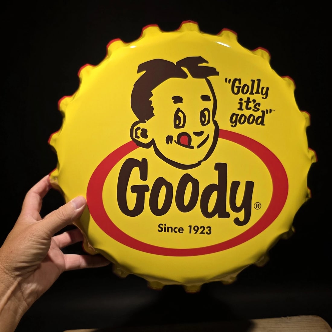 Goody Bottle Cap Sign Embossed Soda Advertising Wall Decor: Reproduction decorative Goody bottle cap sign styled after classic soft drink advertising of the early to mid-20th century. The sign features the familiar "Golly It's Good" slogan and oversized