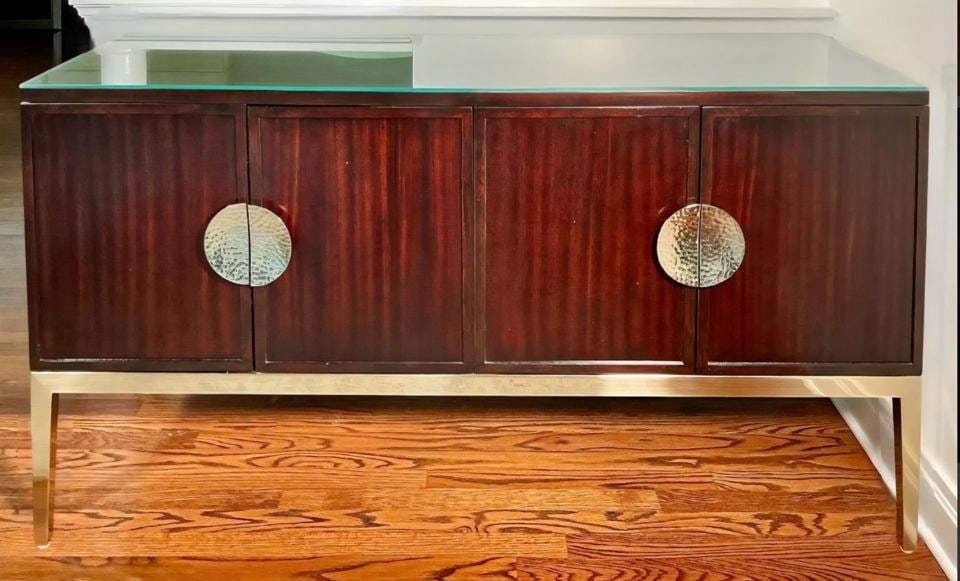Luxury Hi-Design Bernhardt Jet Set Credenza-Sideboard w/ dark wood & polished gold finish metal base: This elegant sideboard has a protective glass top, over two paneled cabinet doors, each fitted with dramatic sculptural silver hardware. Doors open to reveal, on the left, a shelf and flatware drawer,