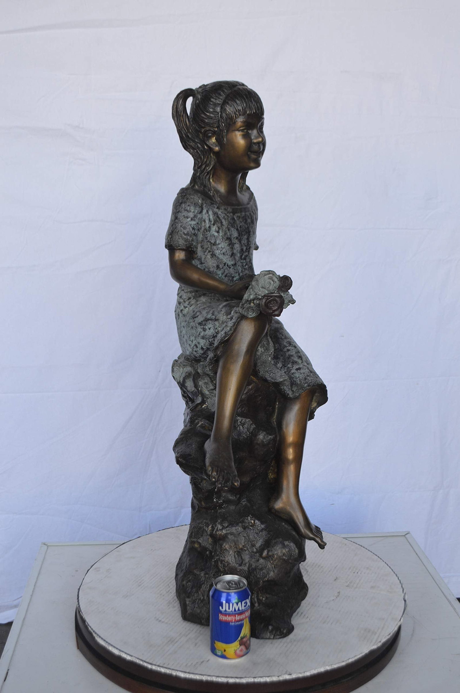 Girl on Tree Trunk Holding Flowers Bronze Statue - Size: 26"L x 11"W x 36"H. - 5