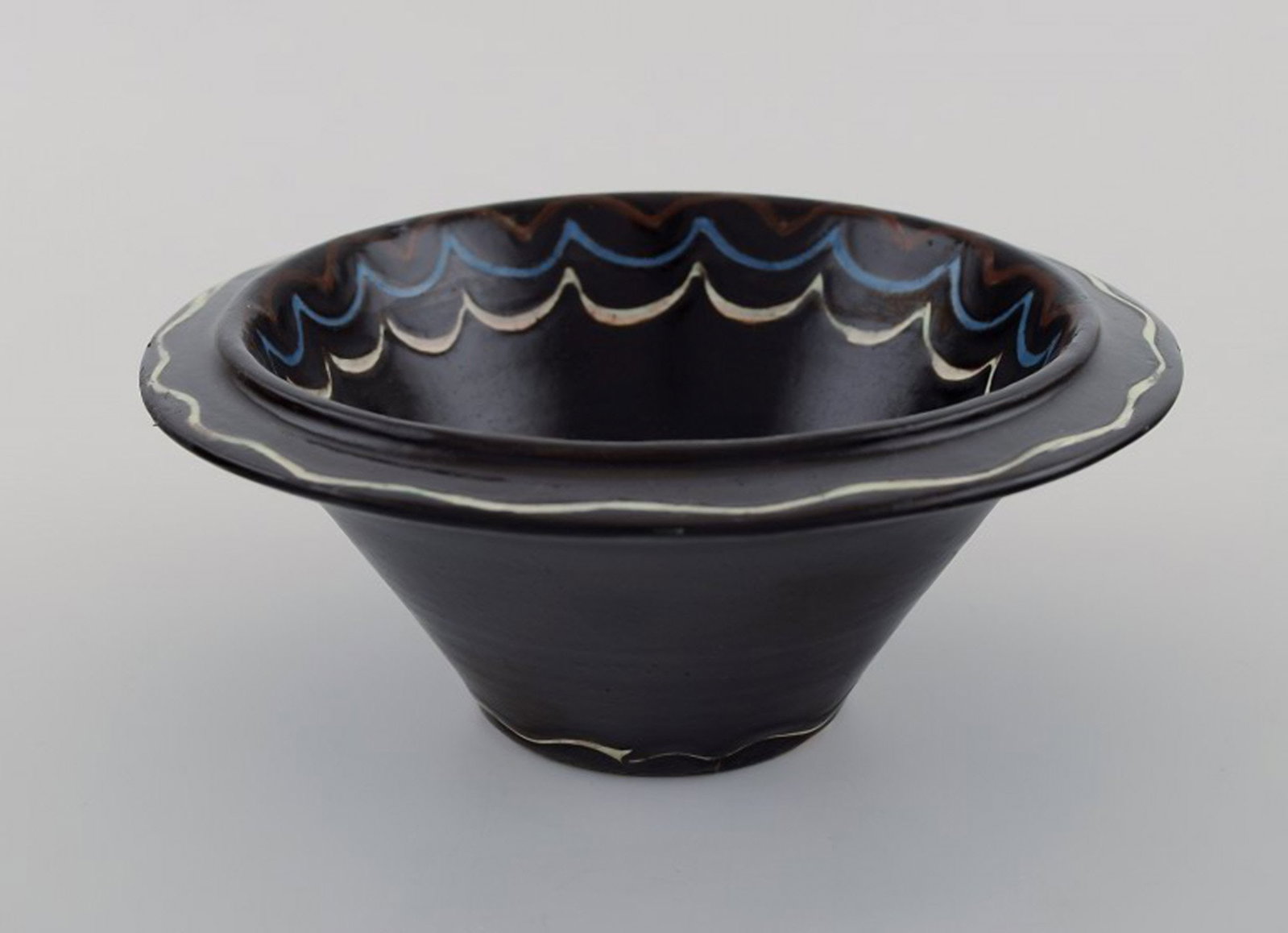 Kahler, Denmark. Bowl in black glazed ceramics with blue and white waves along the edge. 1930s / - 2