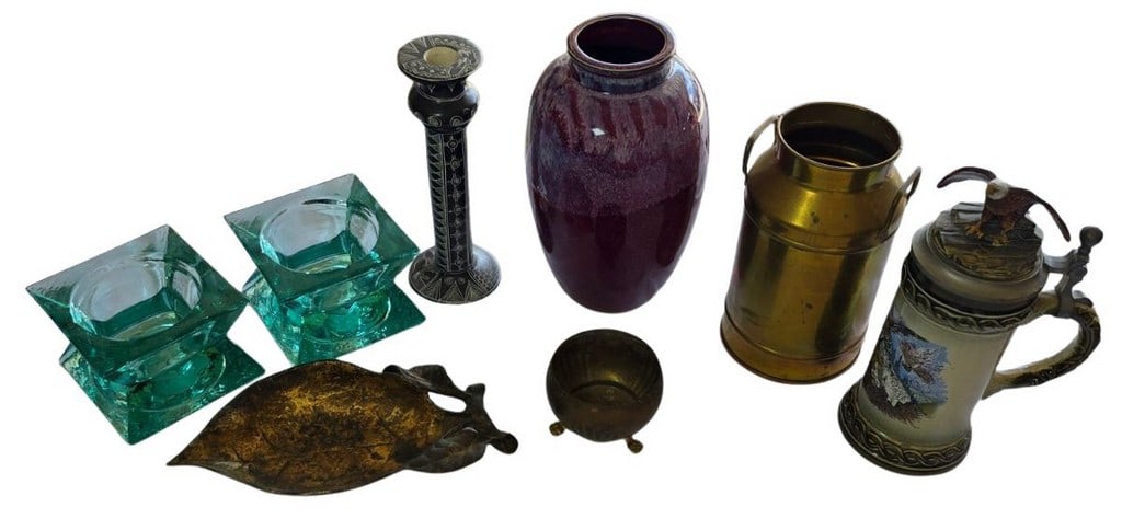 Collection of Decorative Household Items: A diverse collection of decorative household items, including a pair of square green glass candle holders, a carved black ethnic-style candle holder, a large purple ceramic vase, a brass milk jug, a