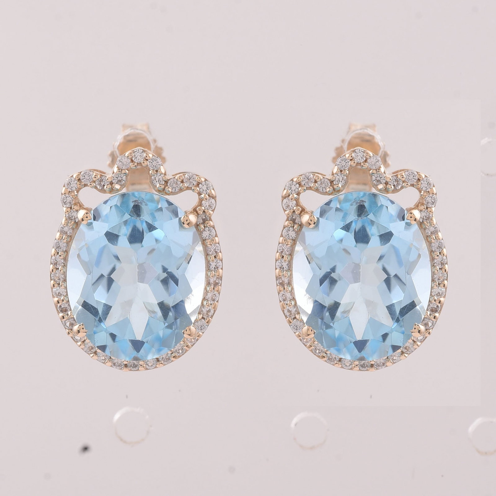 9.24 Ct Oval Blue Topaz 9K Gold Earrings: 9.24 Total Carat Blue Topaz 9K Gold Earrings Specifications: Total Weight 3.686 g Center Gemstone Blue Topaz Gemstone Carat Weight 8.94 Carats Gemstone Measurements 11X9 mm Additional Gemstones White