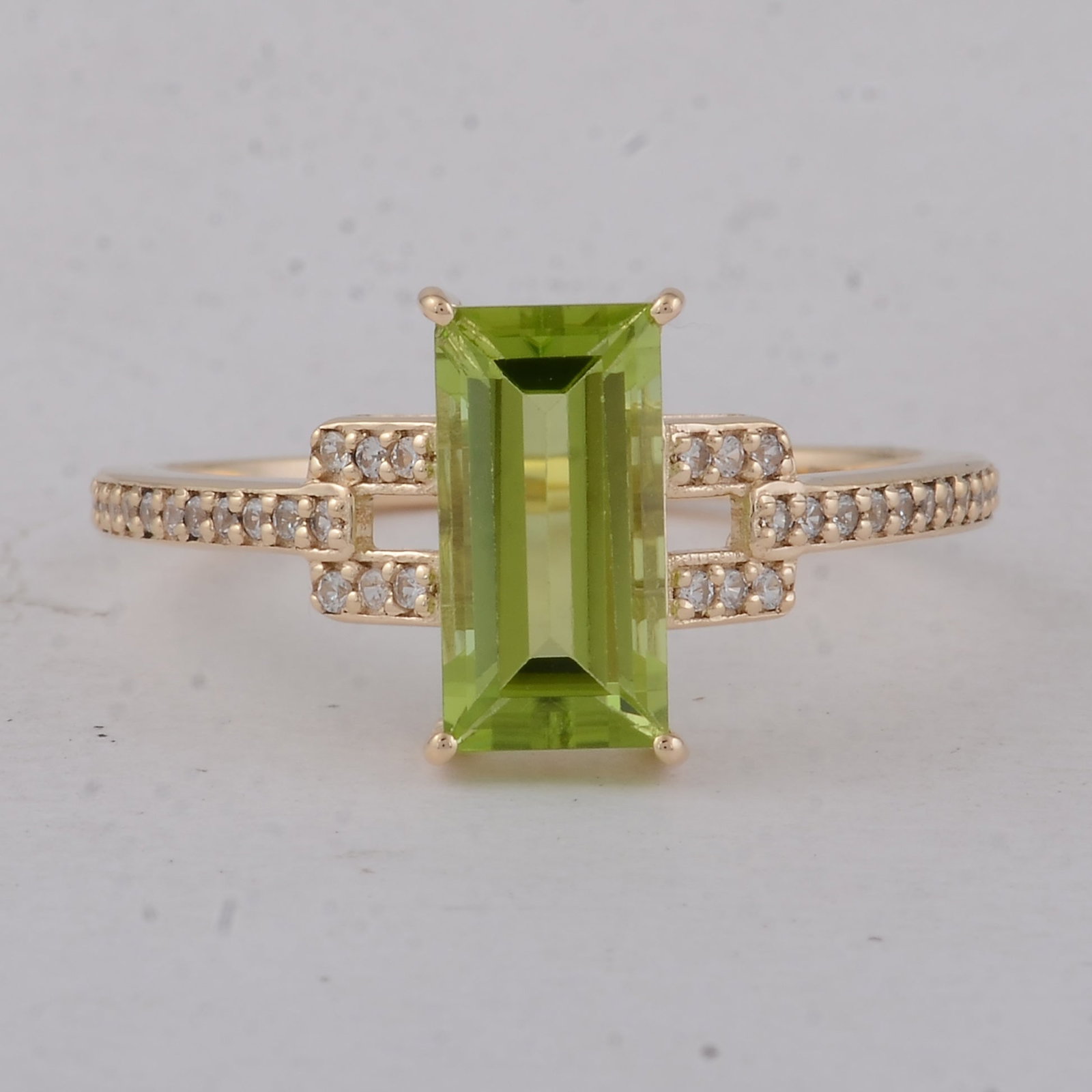 1.96 Ct Baguette Peridot 9K Gold Ring: 1.96 Total Carat Peridot 9K Gold Ring Specifications: Total Weight 1.99 g Center Gemstone Peridot Gemstone Carat Weight 1.8 Carats Gemstone Measurements 10X5 mm Additional Gemstones White Sapphire