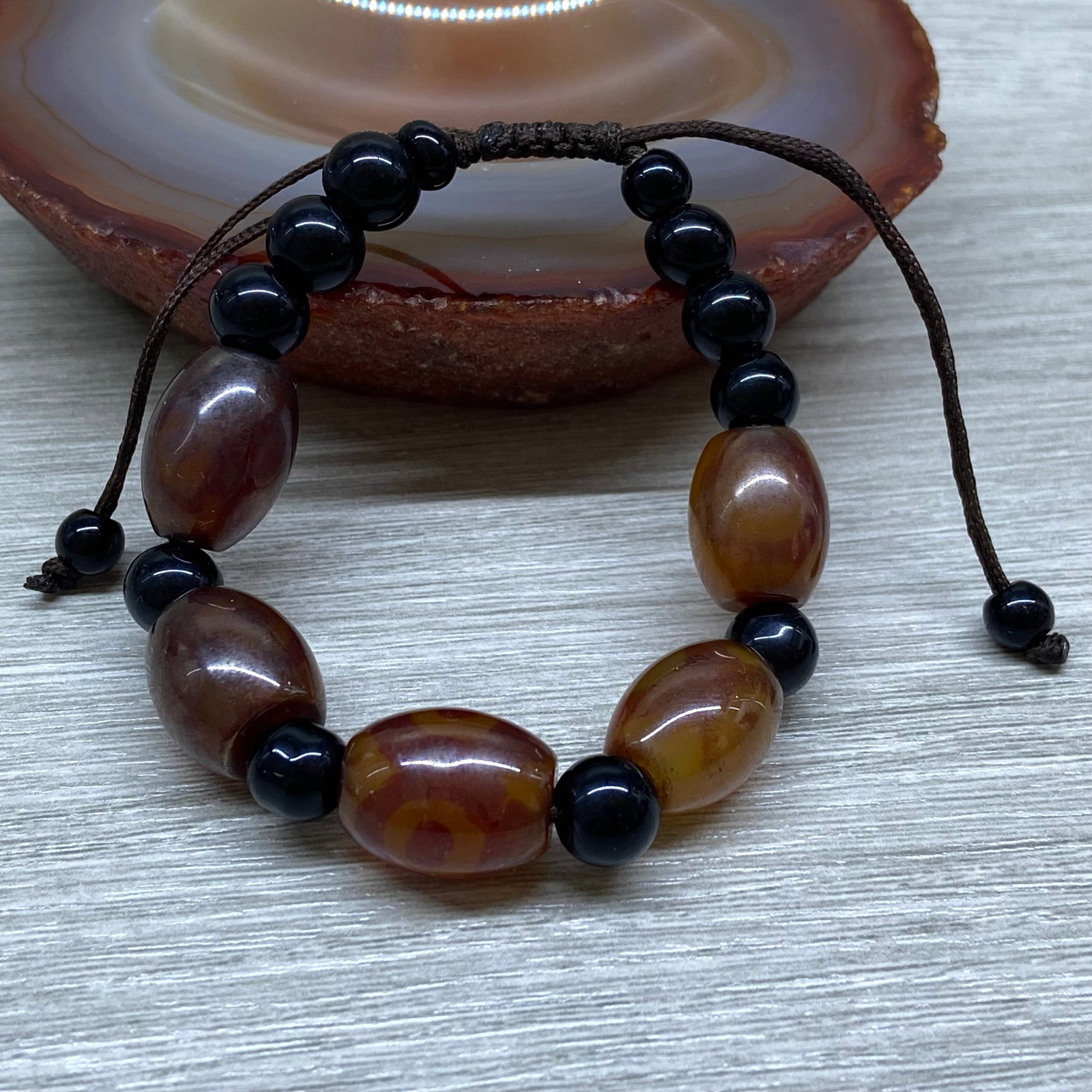 Peking Glass Agate-Inspired Dzi Bead Bracelet with Adjustable Cord: Title: Peking Glass Agate-Inspired Dzi Bead Bracelet with Adjustable Cord Description:Description: A handcrafted bracelet featuring imitation agate dzi beads made of glass. The beads, in warm earthy t