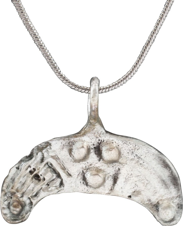 ANCIENT VIKING LUNAR/ASTROLOGICAL PENDANT, C.850-950 AD: Silvered bronze. Just under 1 1/8" (1.15" ) width. Broad crescent with a central triangular panel of three nubs. The flanking panels reeded with nub terminals, executed in different levels of relief, 