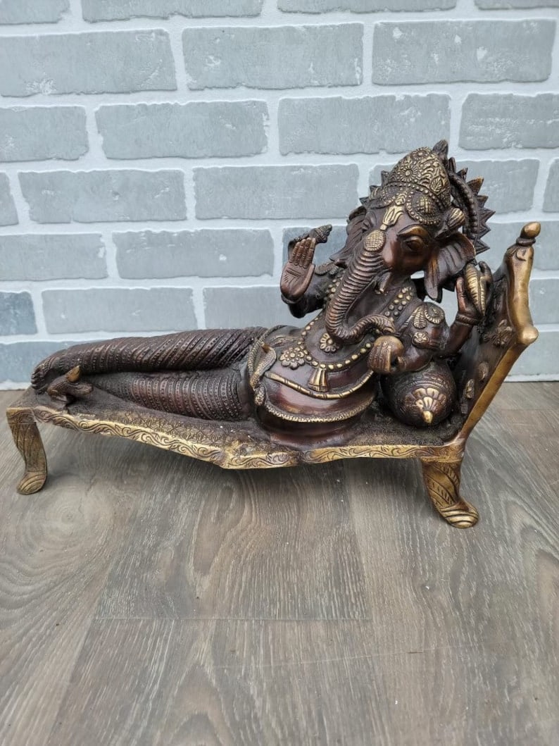 Reclining Ganesha Bronze Statue on Stand: Title: Reclining Ganesha Bronze Statue on Stand Description: "Materials: metal, bronzeWidth: 17.5 inchesHeight: 13 inchesDepth: 7 inchesDescription Reserve: $547.00 Shipping: Domestic: Shipping rates