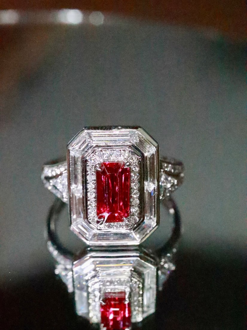 PT950 Natural Ruby Ring: Title: PT950 Natural Ruby Ring Description: This ring features a square-cut ruby with a unique emerald cut style, showcasing a red hue with a hint of rose, and a bright crystal. The PT950 setting adds
