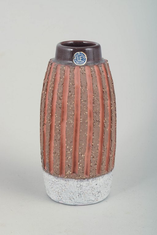 Mari Simmulson for Upsala Ekeby, Sweden. Small cylindrical glazed ceramic vase with narrowed neck.: Mari Simmulson for Upsala Ekeby, vase. Small cylindrical glazed ceramic vase with a slightly narrowed neck. The body is decorated with vertical relief-applied stripes in terracotta tones against a dar