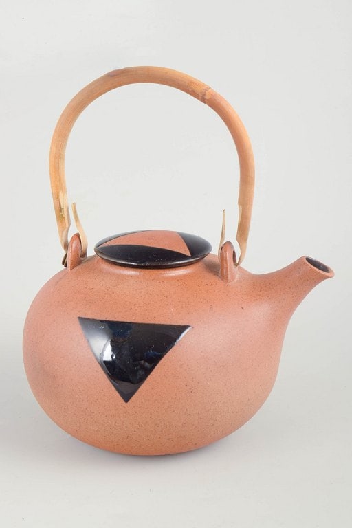 Inger Persson for Rorstrand, Sweden. Stoneware teapot with orange/sand-toned glaze. Approx. 1970s.: Inger Persson for Rorstrand, teapot. Rare stoneware teapot with a matte warm orange/sand-toned glaze and a bold black triangular motif on the body. Fitted with a black lid and a tall swing handle