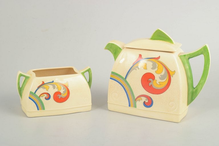 Clarice Cliff for Royal Doulton, England. Faience teapot and sugar bowl with decoration from the: Clarice Cliff for Royal Doulton, teapot and sugar bowl. Art Deco faience teapot and sugar bowl with hand-painted decoration from the "Syren" series. Both pieces feature distinctive angular forms with