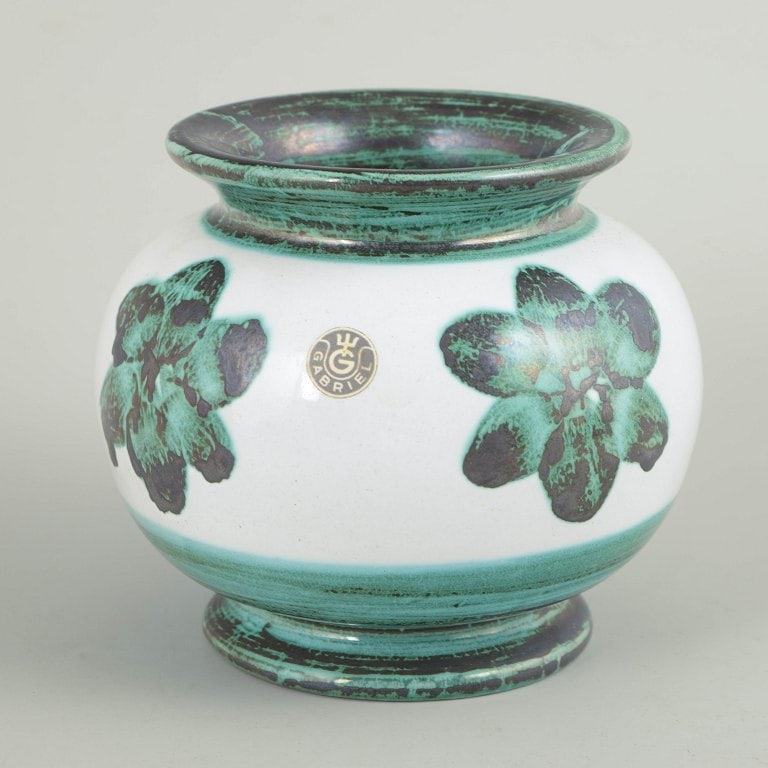 Gabriel Keramik, Sweden. Faience vase with a white ground and floral decoration. Approx. 1940s.: Gabriel Keramik, vase. Globular vase in glazed faience with a white ground and stylised floral decoration in green and dark tones. Accented with a contrasting green rim and foot. Factory sticker with 