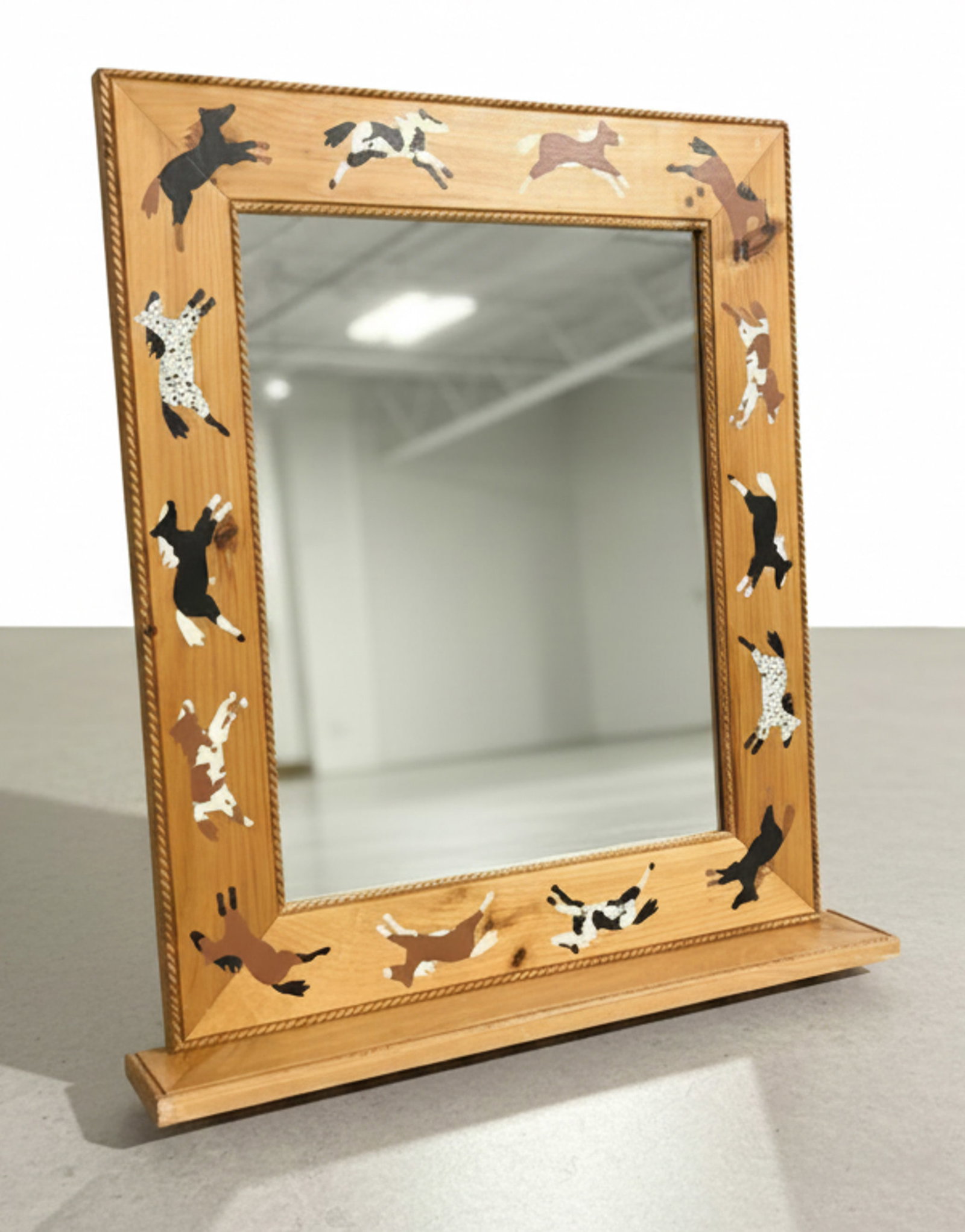 Horse Motif Wooden Framed Vanity Mirror: This charming late 20th-century vanity mirror features a natural wood frame adorned with stenciled or painted horse figures in various poses and coat patterns, including bay, black, and pinto. The