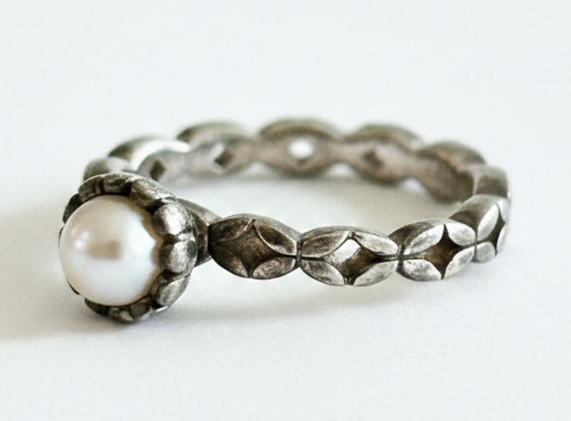 Spinning Sterling Silver and Pearl Ring: A sterling silver ring featuring a single cultured pearl, set in an ornate bezel. The band is decorated with a repeating pattern and is marked "SPINNING" and "925". Jewelry Type: Ring Metal: Sterling 