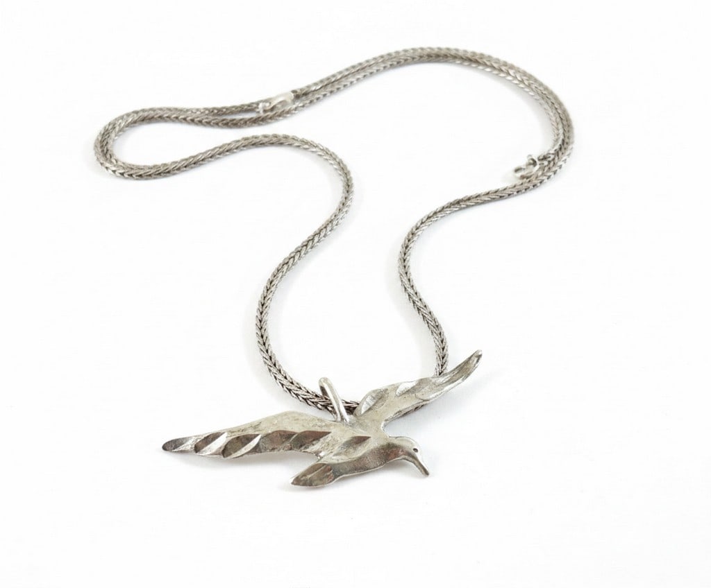 Sterling Silver Soaring Bird Pendant Necklace: A sterling silver necklace featuring a pendant designed as a soaring bird. The bird has textured wings and a smooth body. The pendant is attached to a wheat chain with a spring ring clasp. Hallmarks