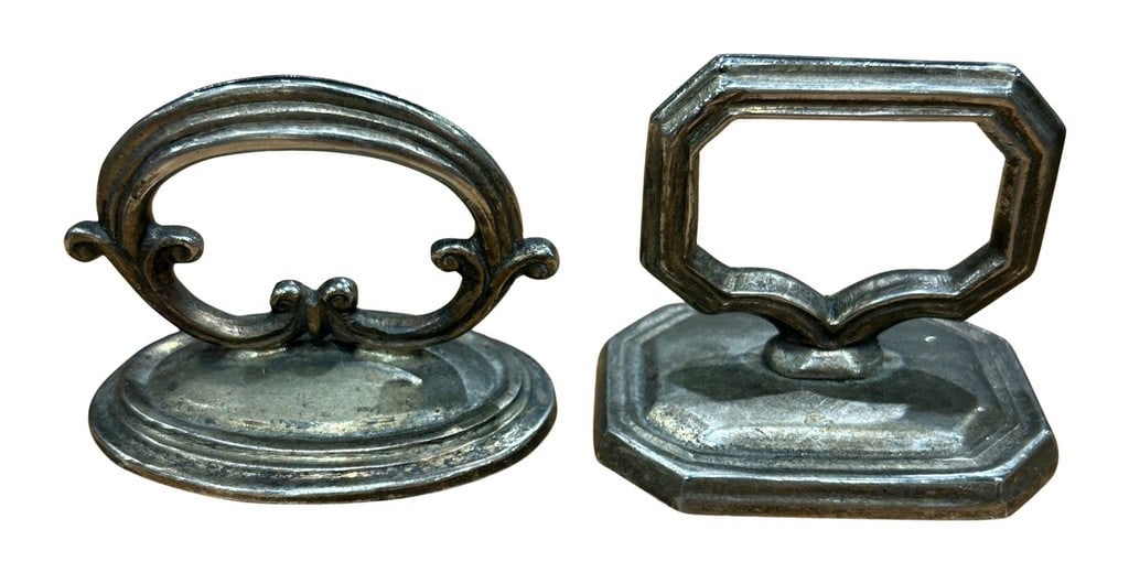 Set of Two Silver-Tone Metal Drop Pulls: This lot features a set of two silver-tone metal drop pulls, possibly brass or pewter, showcasing a classical design with octagonal escutcheon plates and a ring pull. The hardware appears to be in an